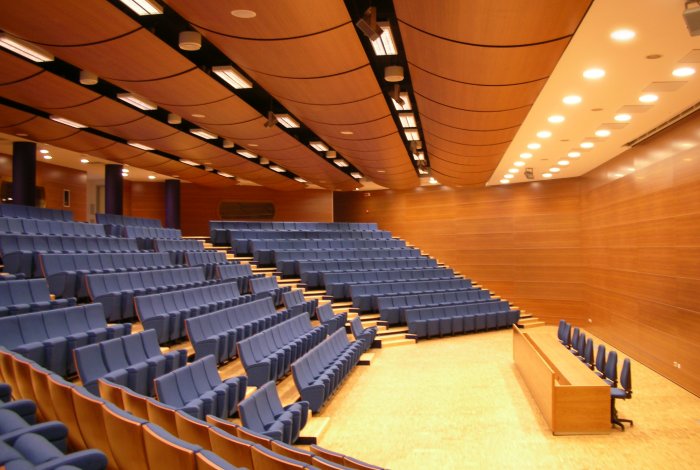 Auditorium di Mestre con poltrone blu, podio relatore e rivestimento pareti e soffitto in legno