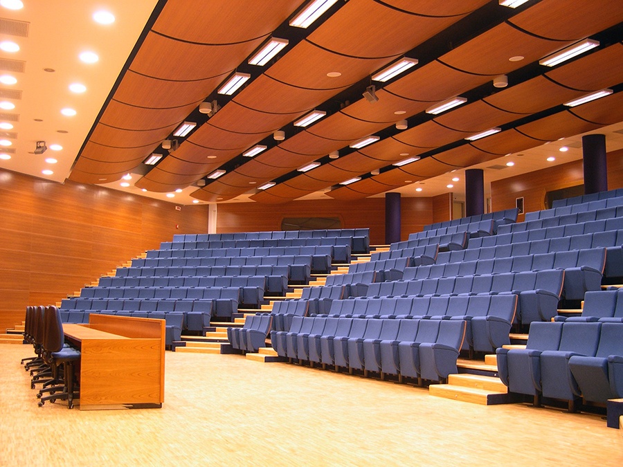 Auditorium di Mestre con poltrone blu a gradoni, leggio in legno e pannelli acustici in legno