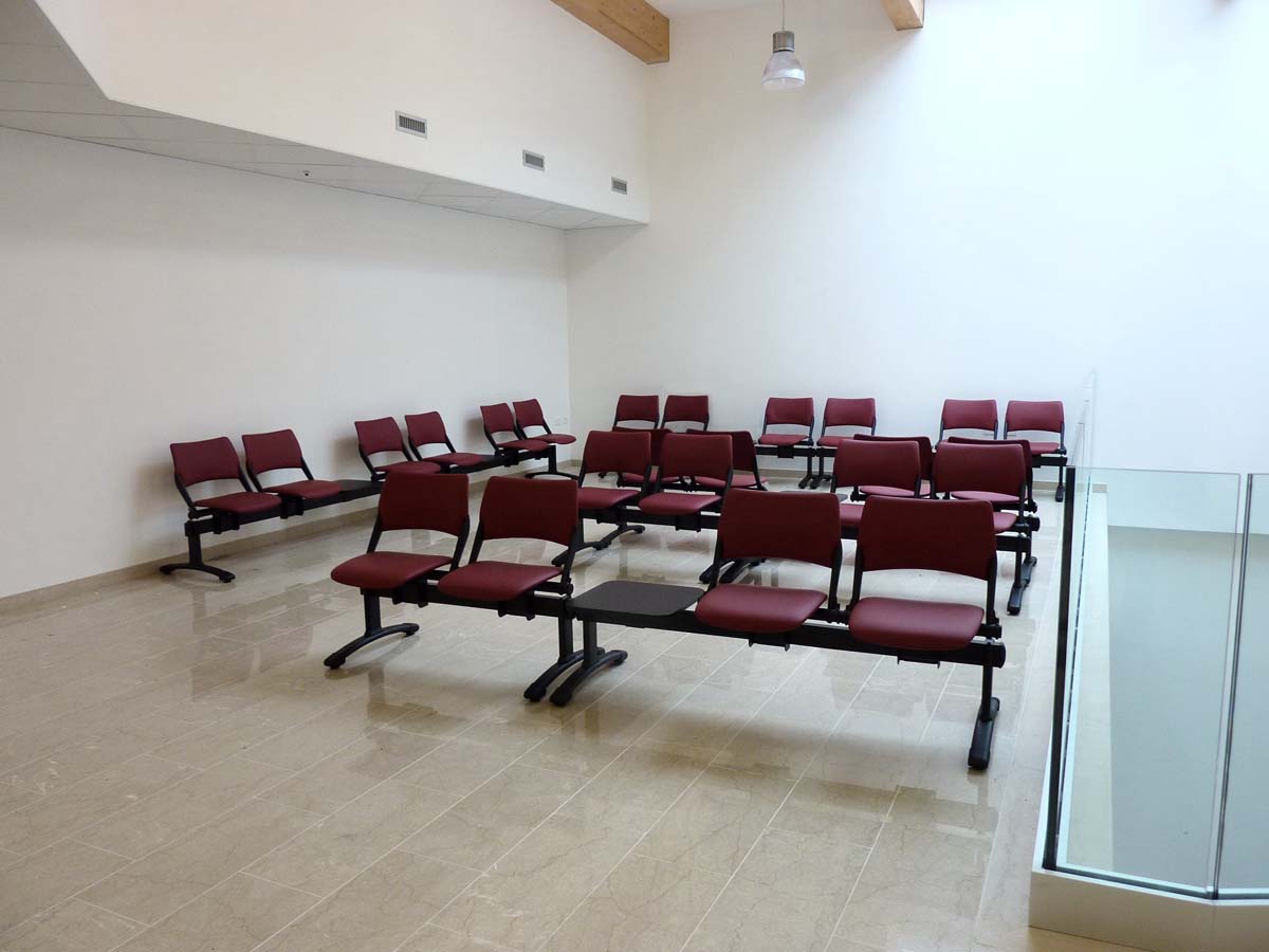 Sala di attesa USSL Feltre con sedute rosse su trave metallica e pavimento in marmo