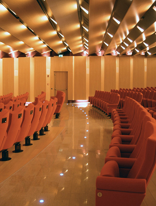 Corridoio centrale con poltrone rosse e pannelli in legno nella sala Camera di Commercio di Lecco