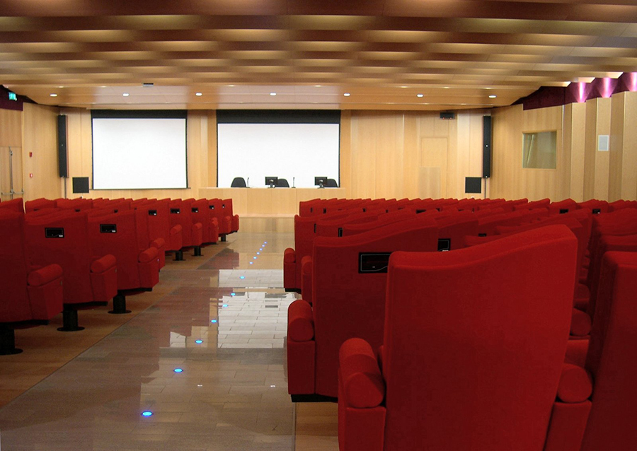 Sala conferenze Camera di Commercio Lecco con poltrone rosse, doppio schermo e tavolo relatori