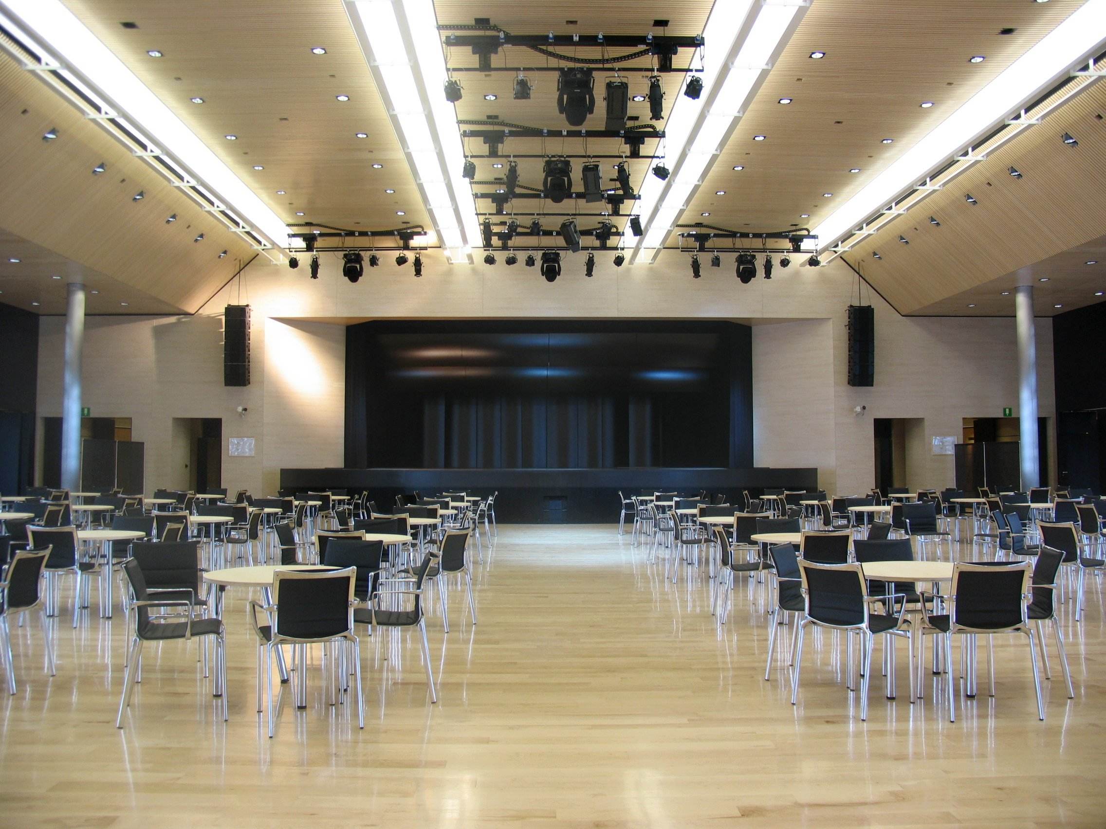 Sala eventi del Casino di Campione d'Italia con tavoli, sedie e palco con impianto luci