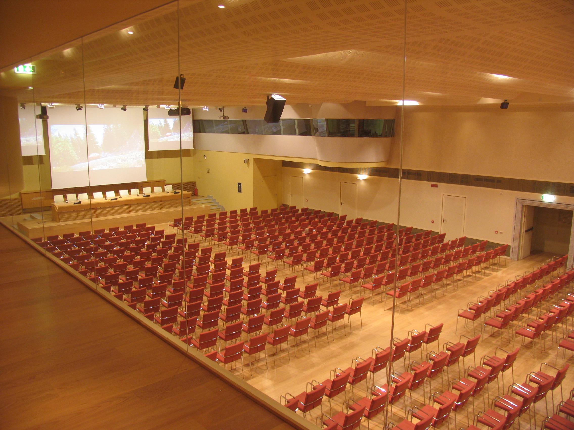 Sala congressi di Villa Borromeo con poltrone rosse, schermo di proiezione e impianto audio-video