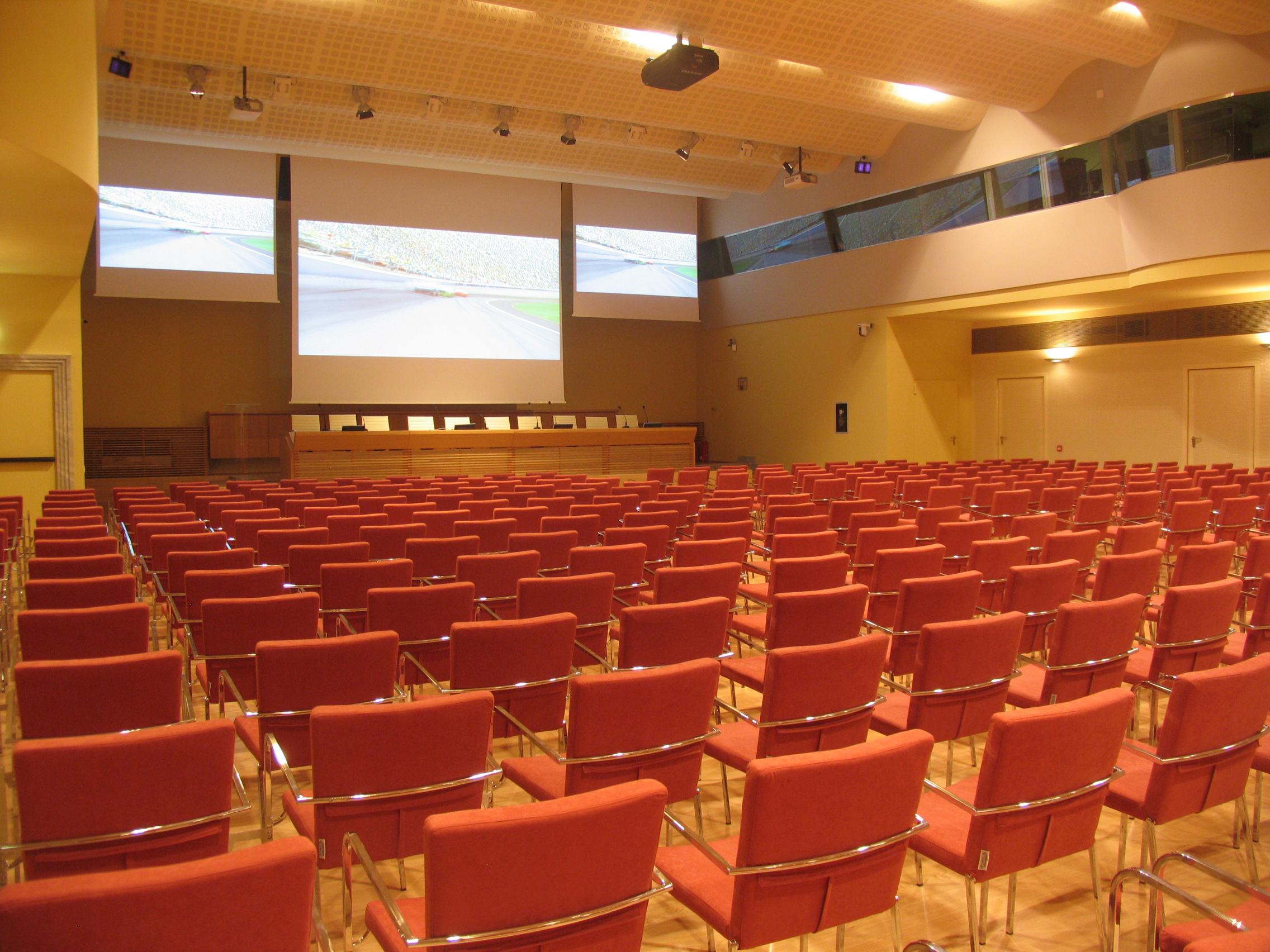 Poltrone rosse e doppio schermo di proiezione nella sala congressi di Villa Borromeo