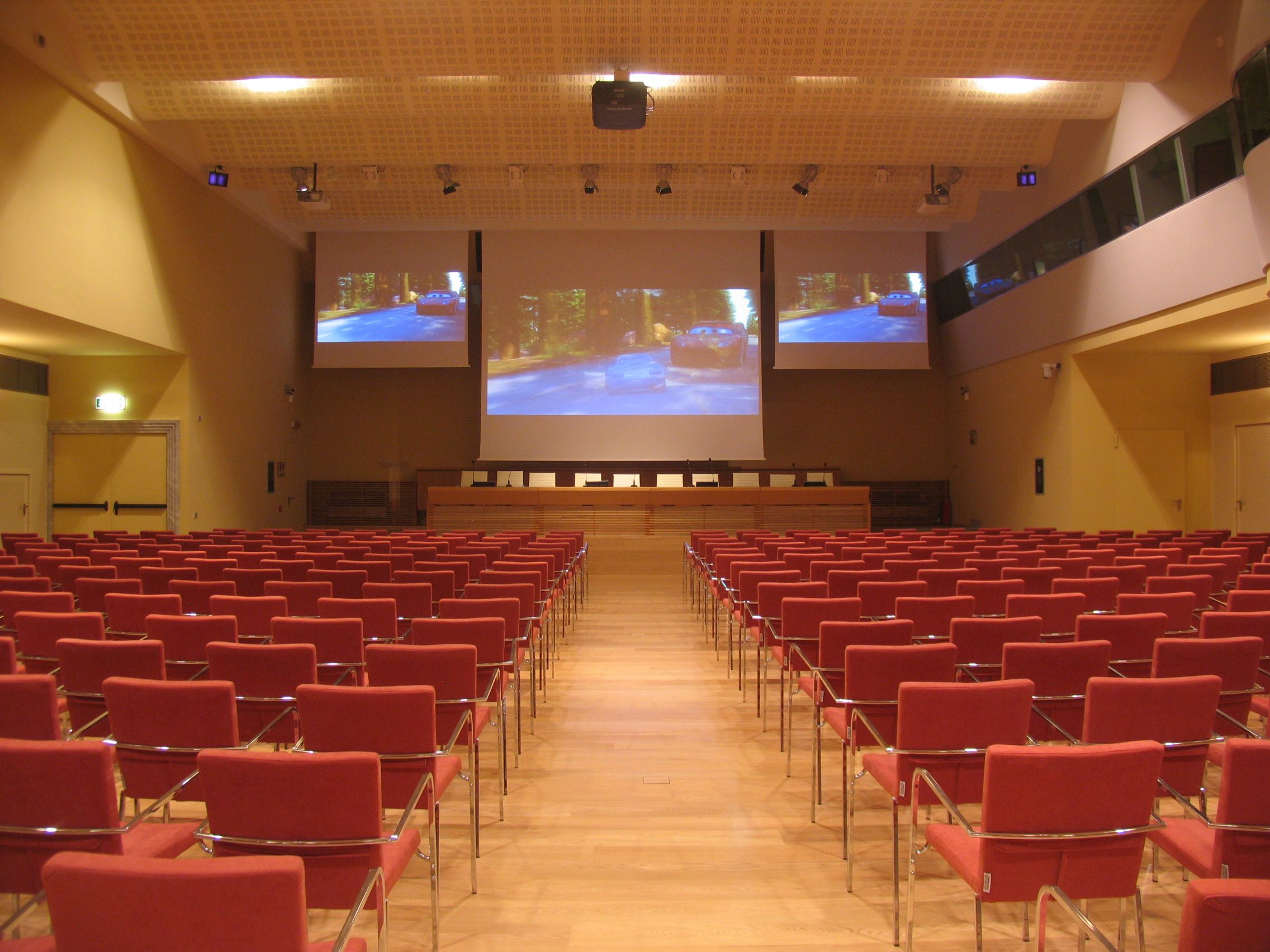 Sala congressi di Villa Borromeo con poltrone rosse, proiettore e schermi di proiezione