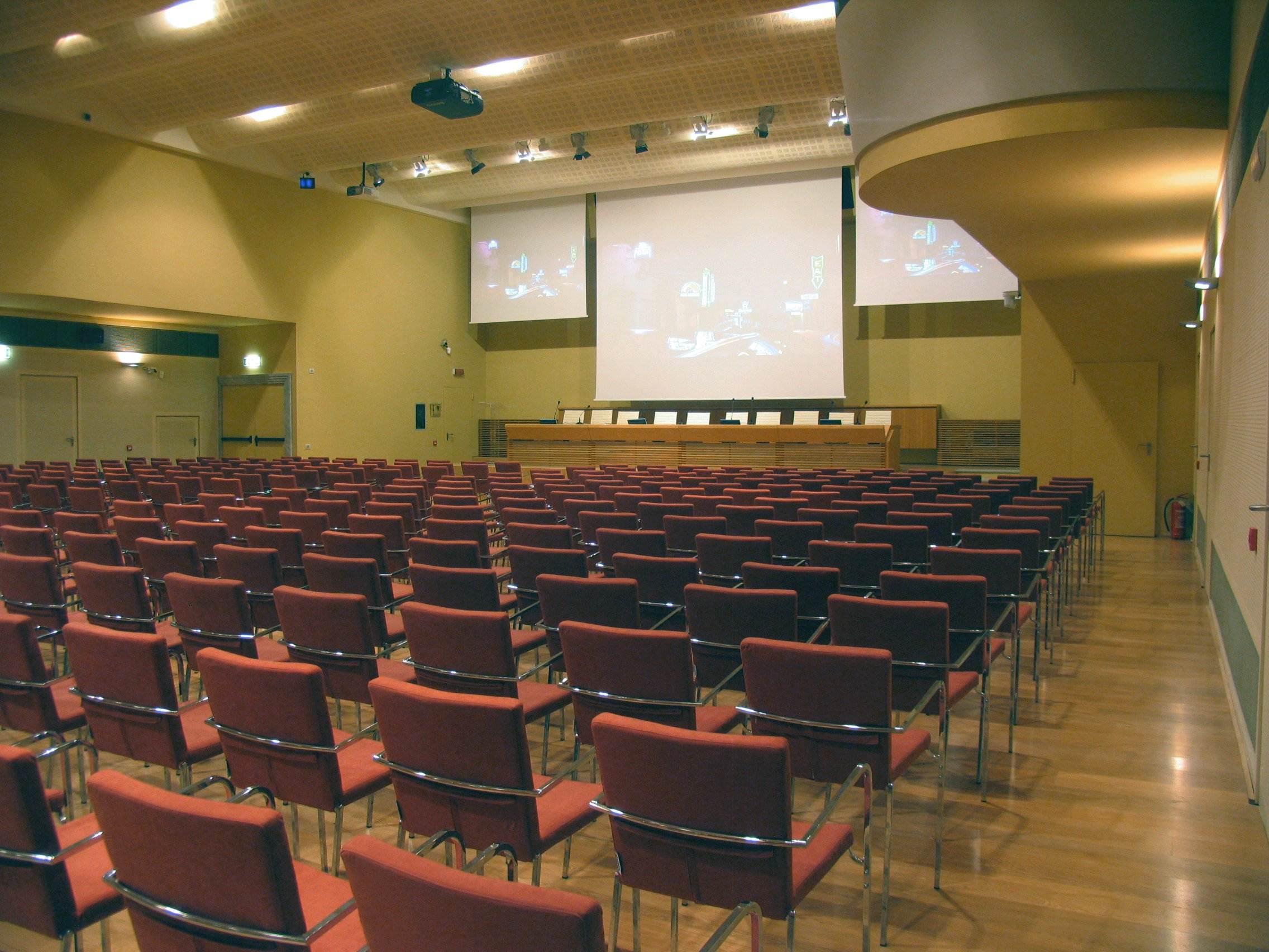 Sala congressi di Villa Borromeo con schermi di proiezione, proiettore e poltrone rosse