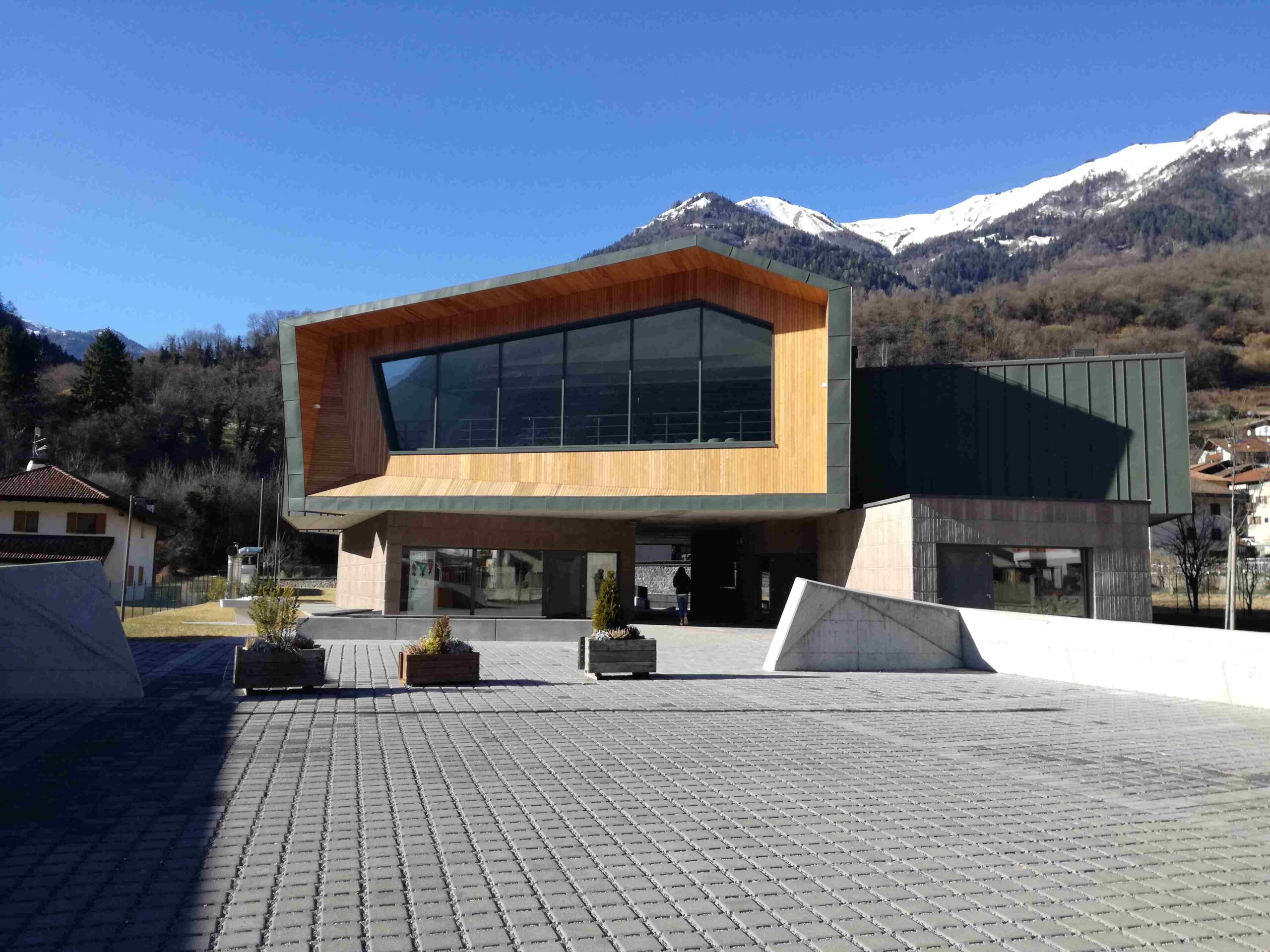 Esterno del Centro Giovani di Pieve di Bono con architettura moderna e montagne innevate