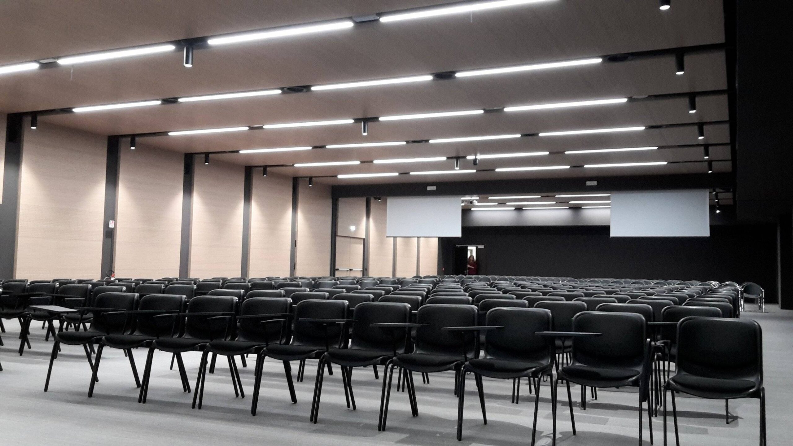 Vista posteriore dell'auditorium del Centro Studi Erickson con sedie nere e schermi di proiezione