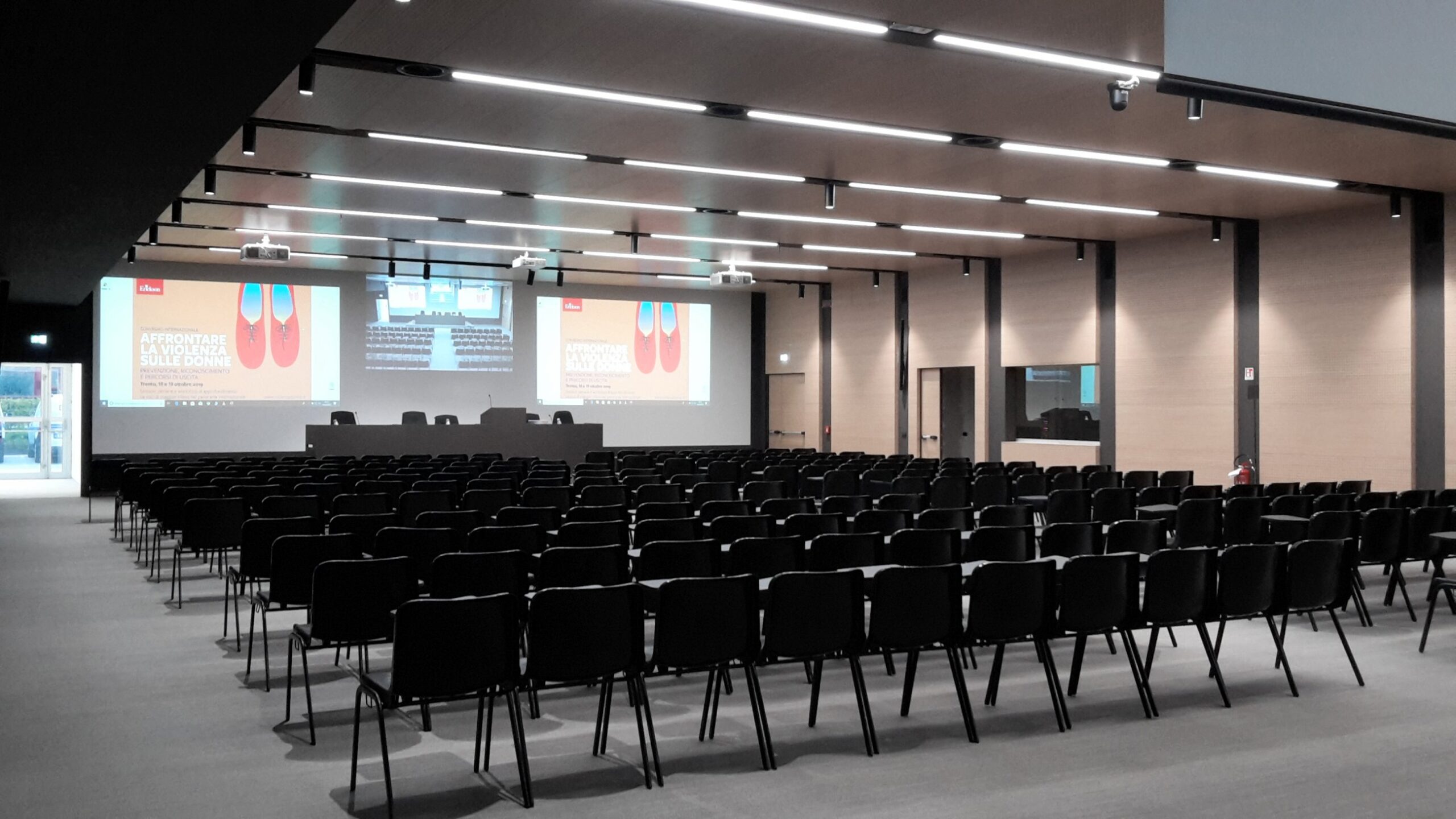 Sala conferenze del Centro Studi Erickson con presentazione attiva su doppio schermo e sedie nere