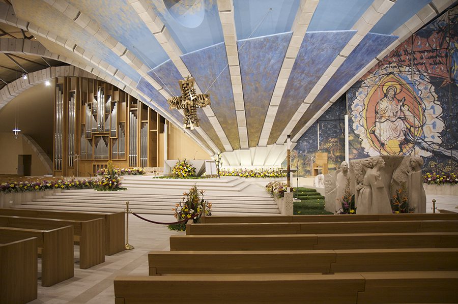 Interno della Chiesa di Padre Pio con altare, panche in legno, organo e mosaico raffigurante Cristo risorto