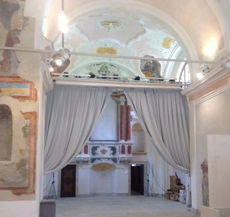 Interno della Chiesa di Sant Andrea a Breguzzo con tendaggi, traliccio luci e schermo di proiezione
