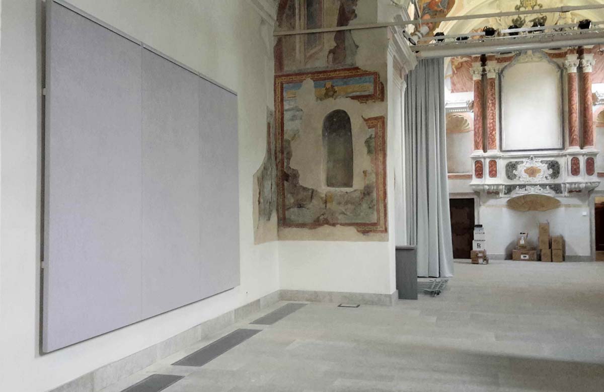 Pannello fonoassorbente a parete nella Chiesa di Sant Andrea a Breguzzo con affreschi storici visibili