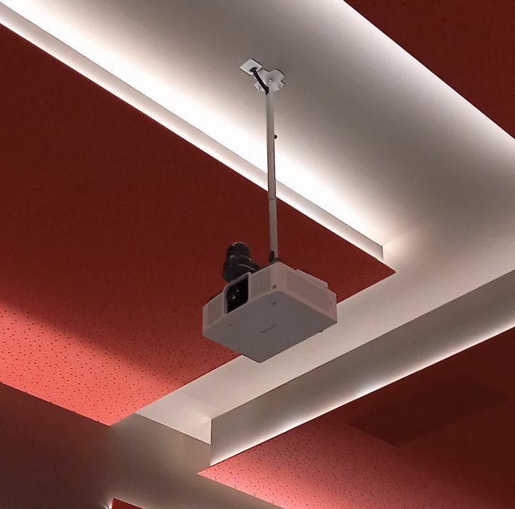 Videoproiettore a soffitto con pannelli acustici forati rossi al Cinema Teatro Ferrari di Galbiate