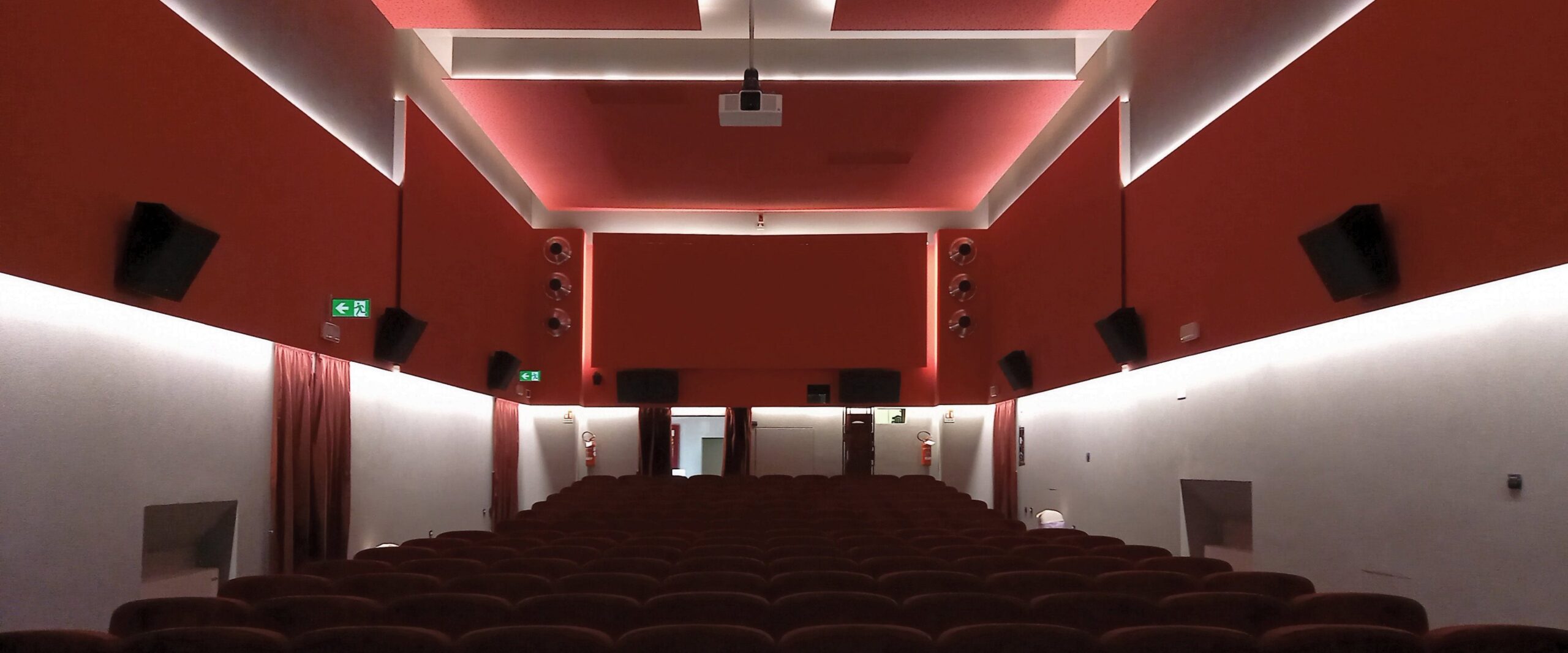 Panoramica della sala cinema del Teatro Ferrari di Galbiate con poltrone, diffusori e illuminazione rossa