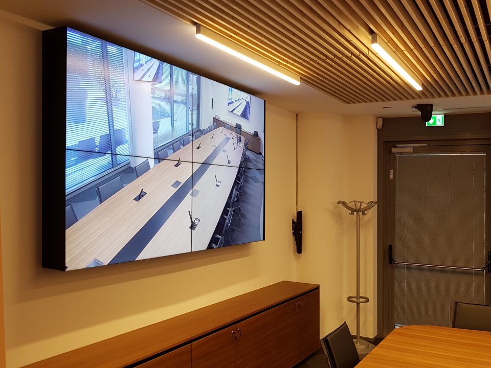 Videowall a parete nella sala riunioni della sede Confcommercio Trento con soffitto in legno