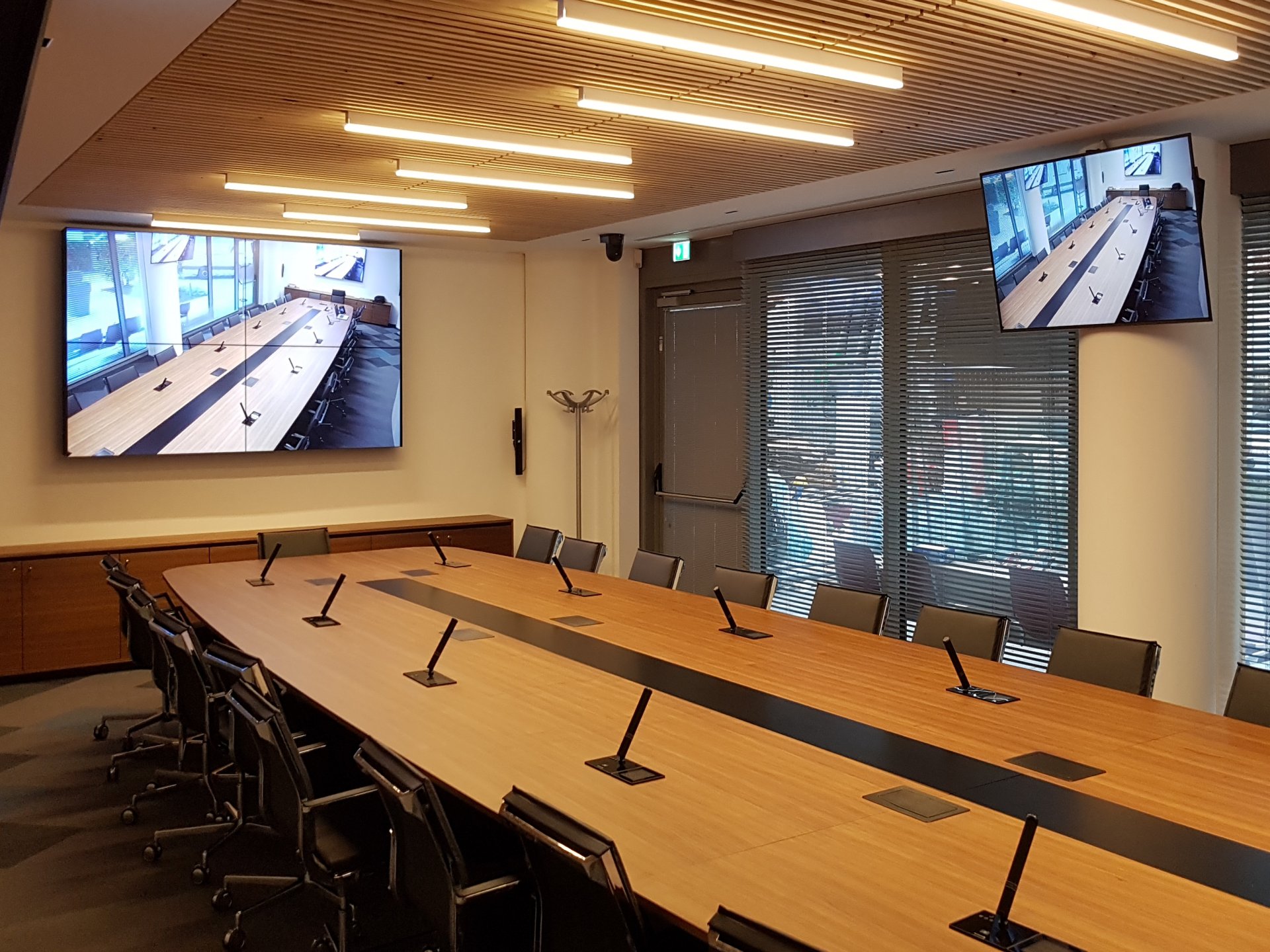 Sala riunioni Confcommercio Trento con tavolo conferenze, microfoni e doppio schermo video