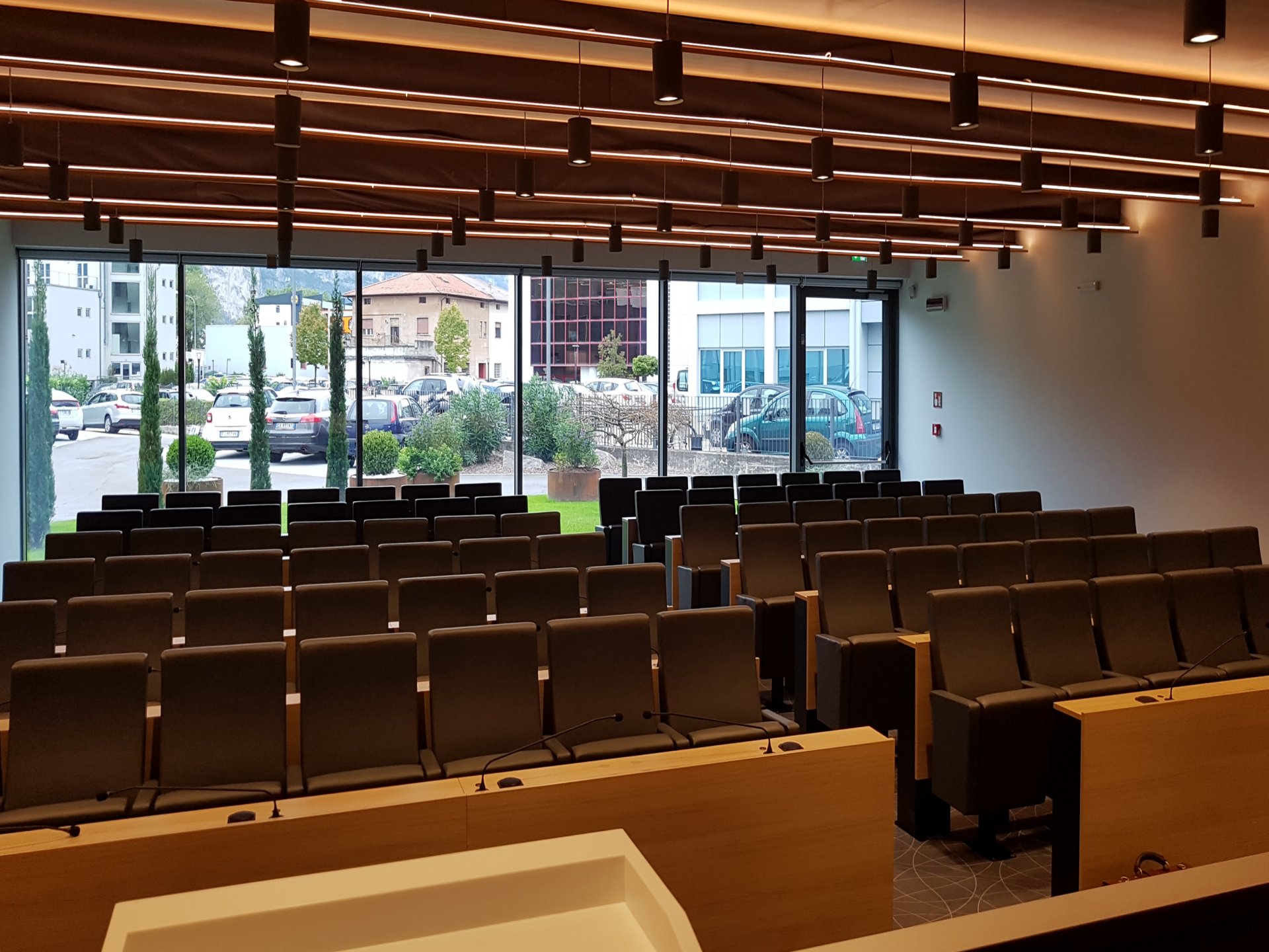 Sala conferenze Confcommercio Trento con poltrone, microfoni da tavolo e vetrate panoramiche