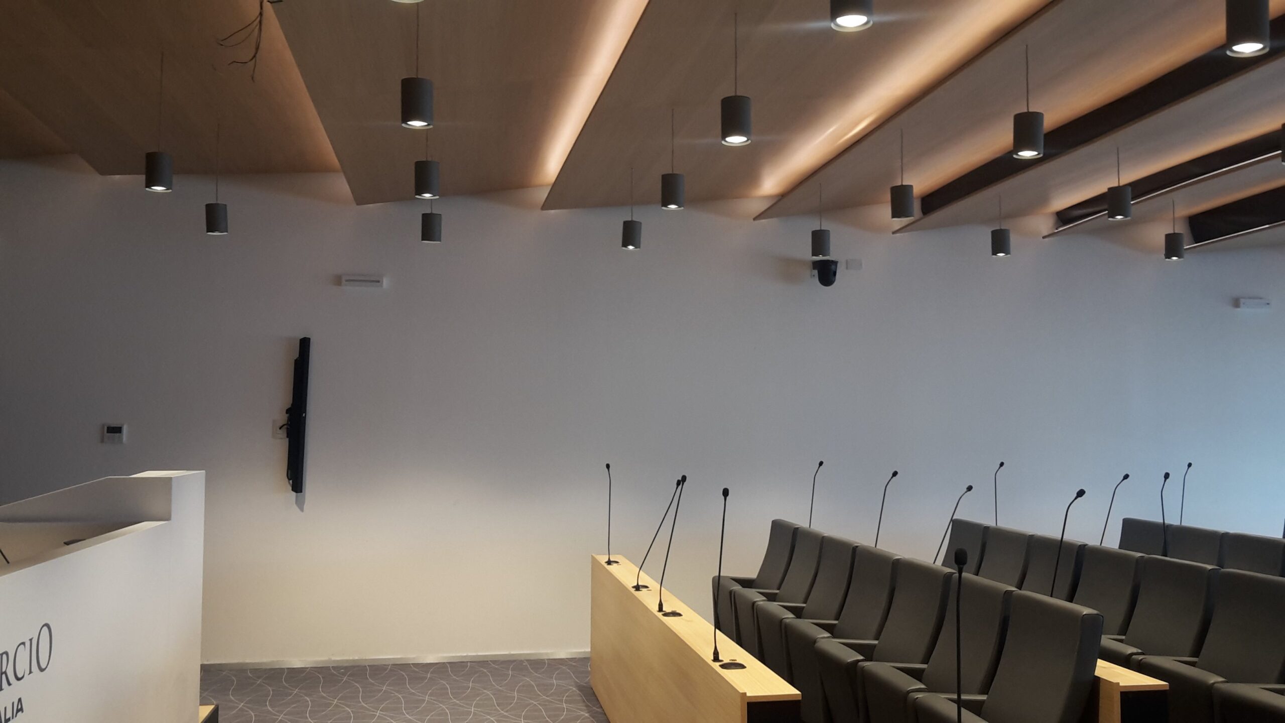 Postazioni con microfoni, telecamera PTZ e faretti a soffitto nella sala conferenze Confcommercio Trento