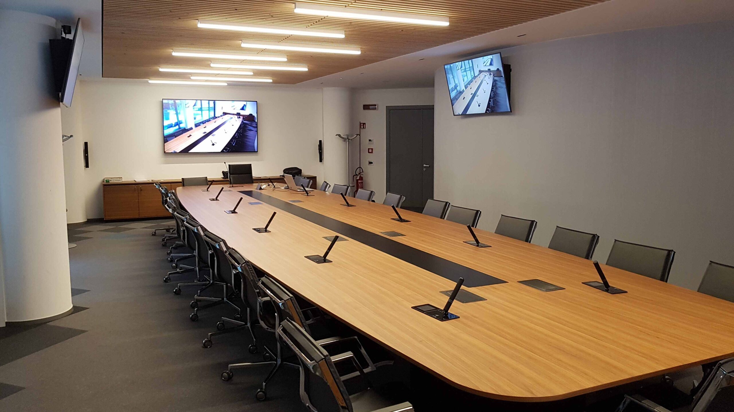 Sala riunioni Confcommercio Trento vista laterale con tavolo conferenze, microfoni e schermi