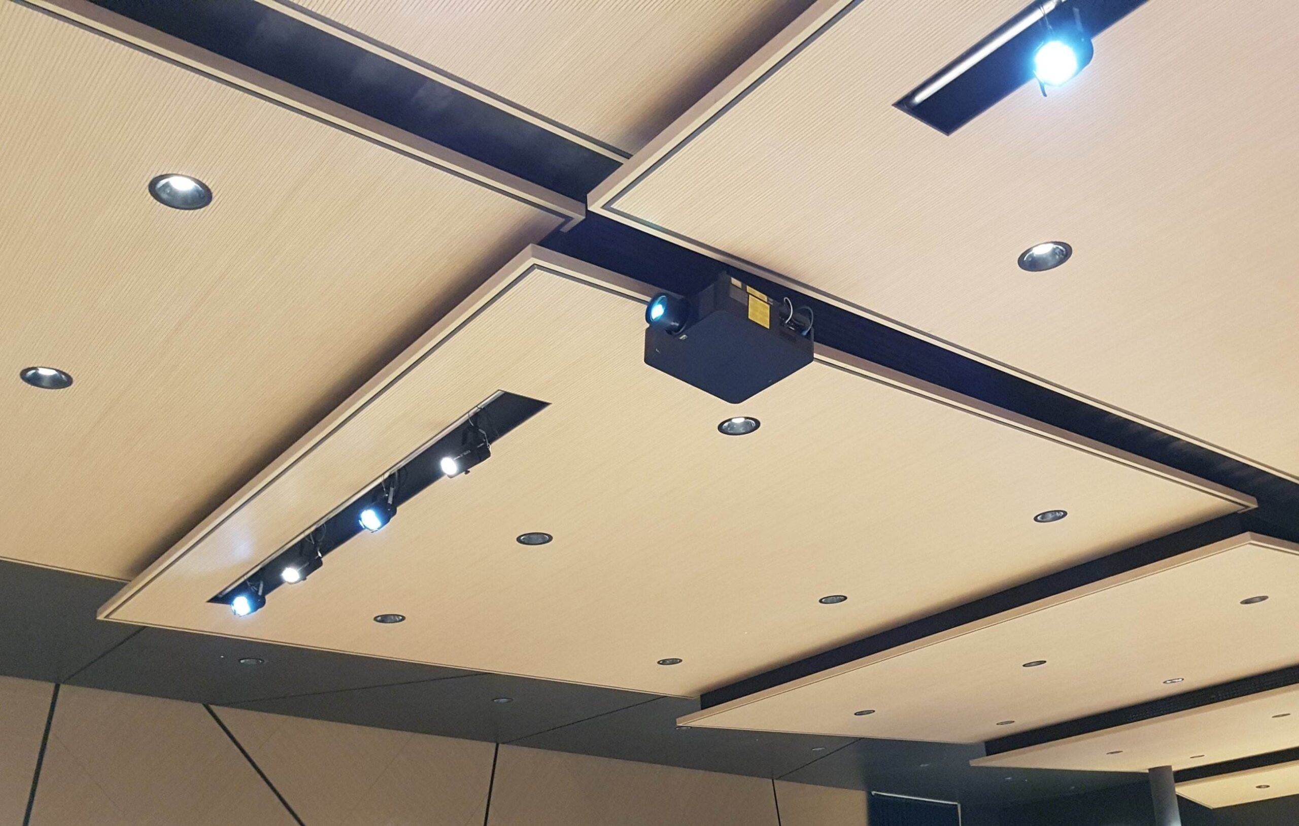 Soffitto con pannelli acustici in legno, proiettore e faretti nell auditorium Cooperativa Sant Orsola