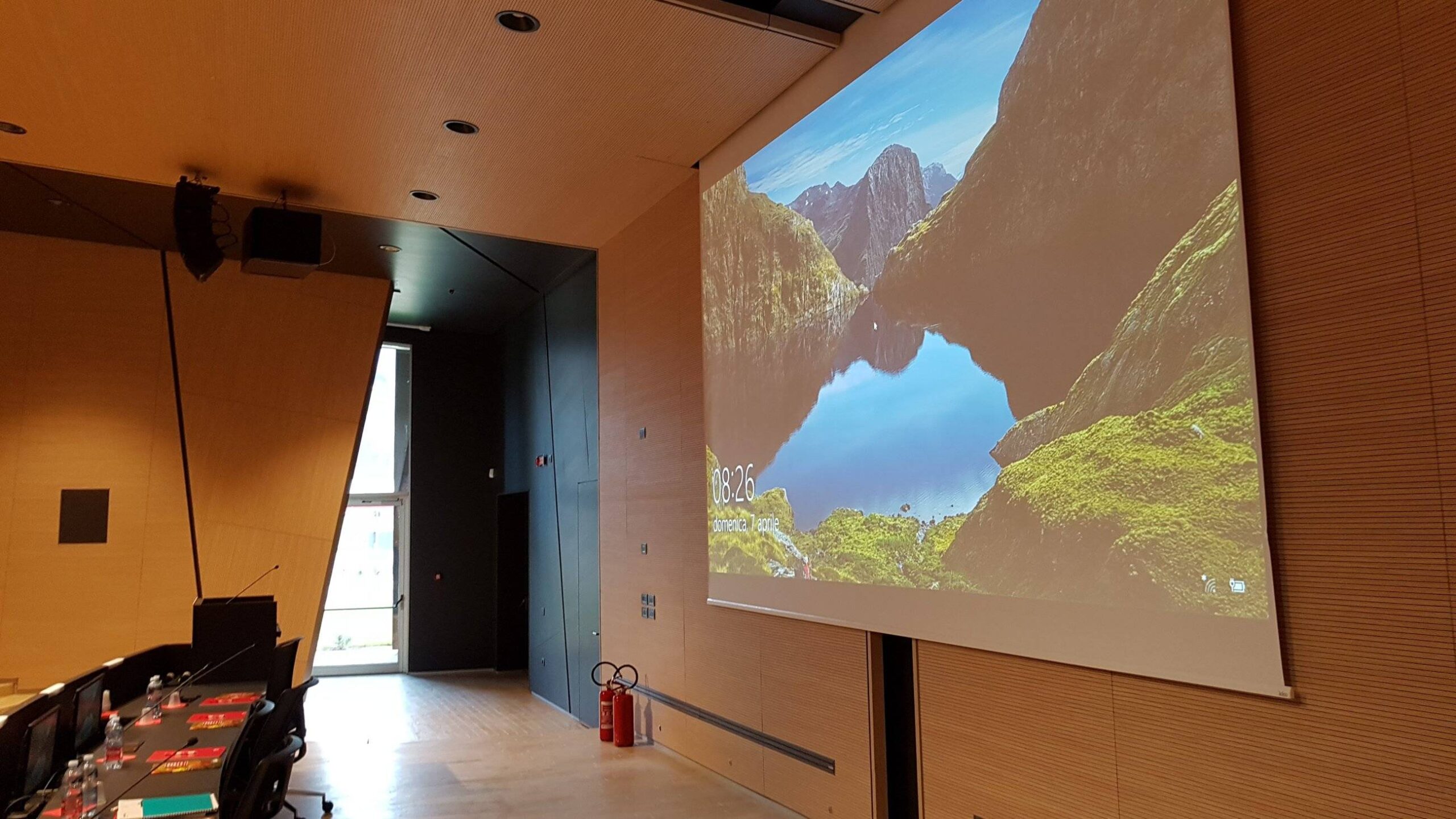 Schermo di proiezione attivo e diffusori audio a parete nell auditorium della Cooperativa Sant Orsola