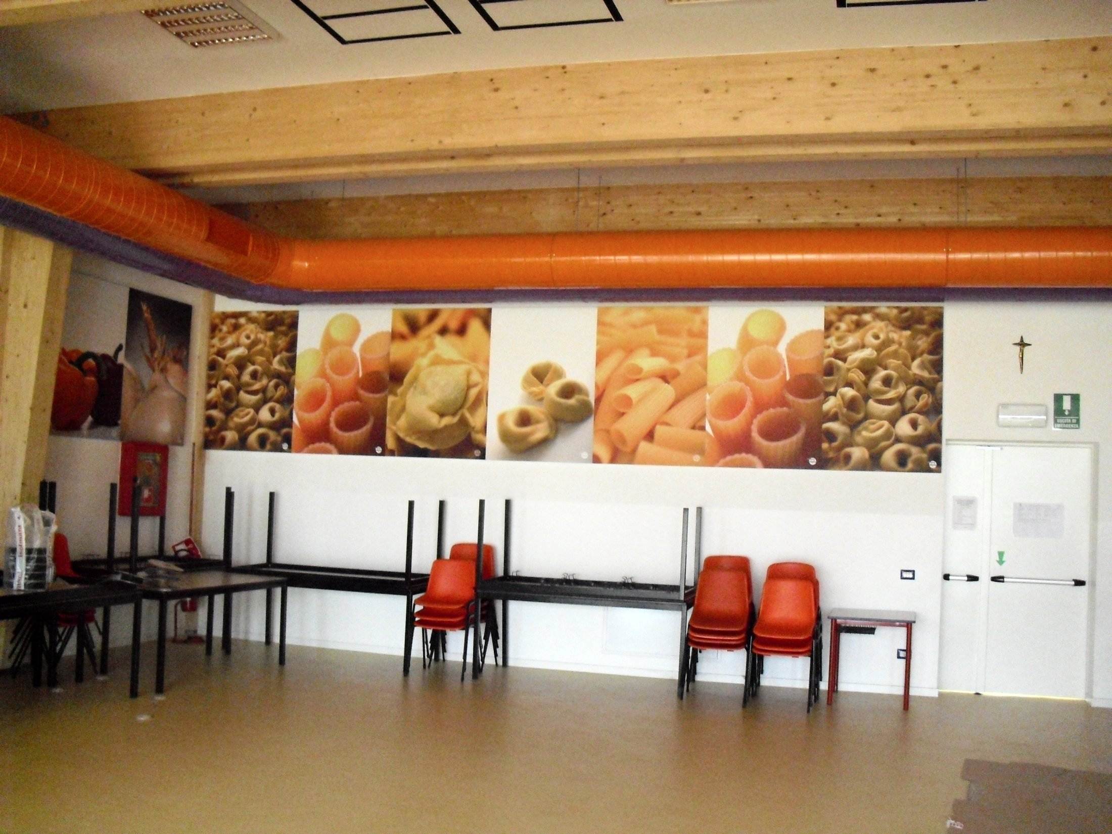 Parete della mensa con pannelli decorativi e canale di ventilazione arancione a soffitto