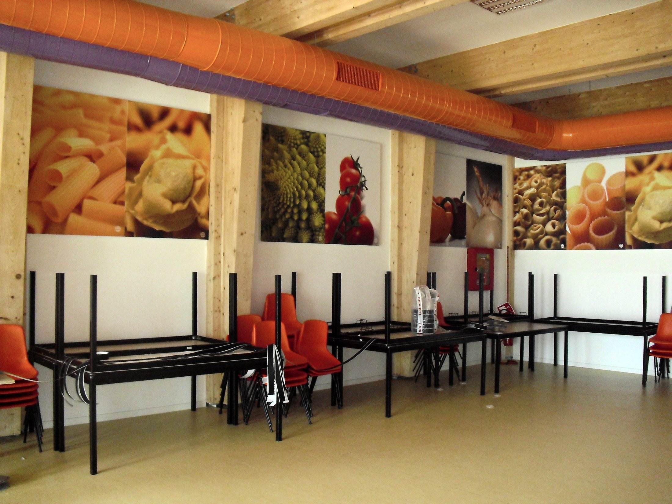 Mensa durante i lavori di correzione acustica con tavoli impilati e pannelli a parete