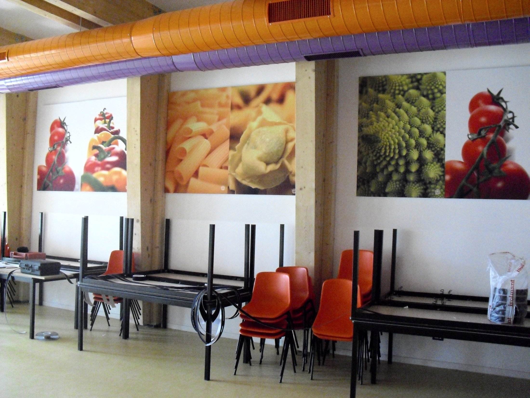 Dettaglio dei pannelli fonoassorbenti decorativi a parete nella mensa con travi in legno