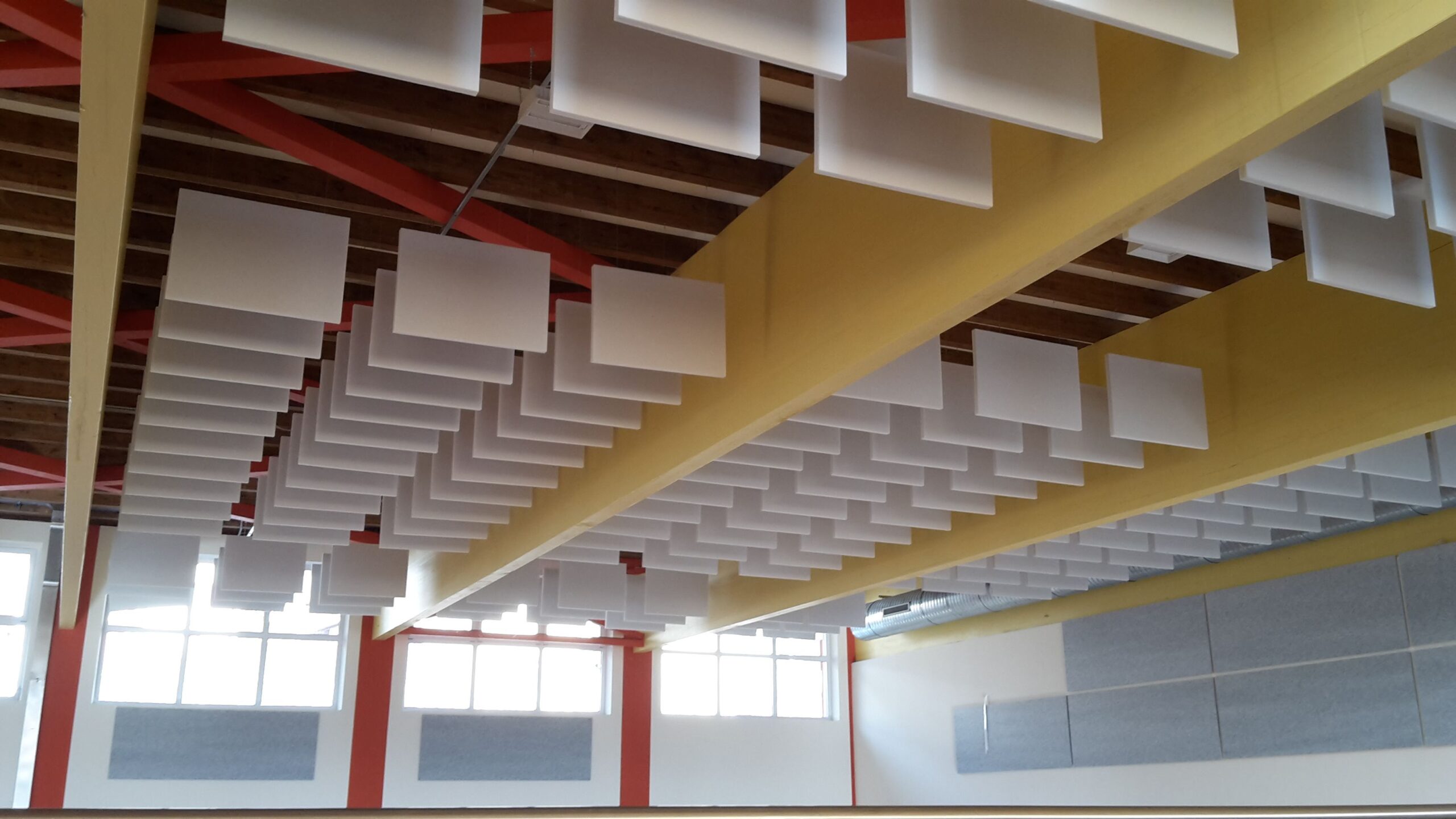 Dettaglio dei baffles acustici sospesi e pannelli a parete in palestra con struttura in acciaio