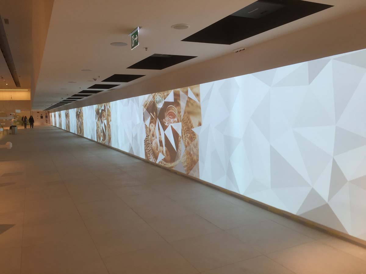 Corridoio con grande parete video retroilluminata e proiezioni nel padiglione Expo Milano 2015
