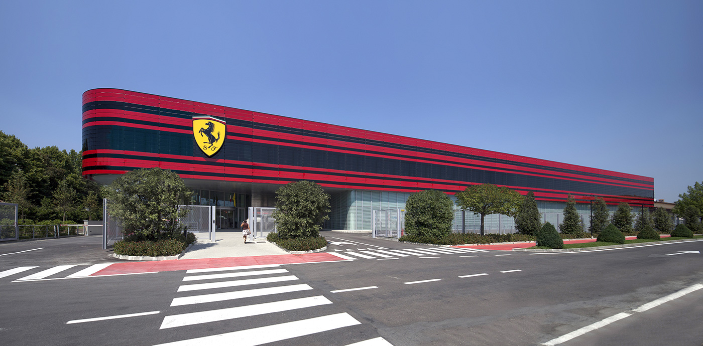 Esterno dello stabilimento Ferrari a Maranello con facciata rossa e logo del Cavallino Rampante