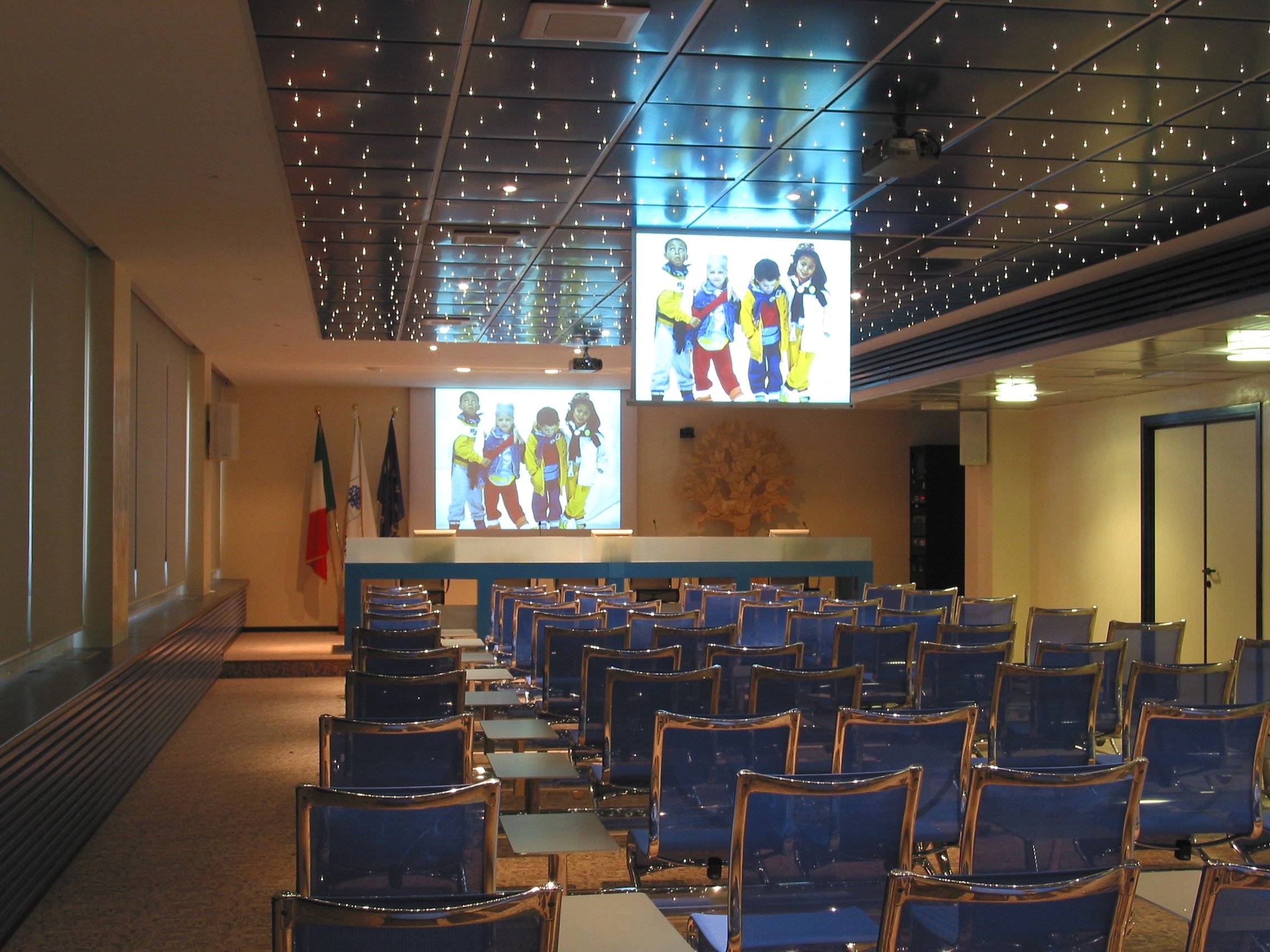 Sala conferenze Foppa Pedretti con proiettore, sedute blu e controsoffitto effetto cielo stellato