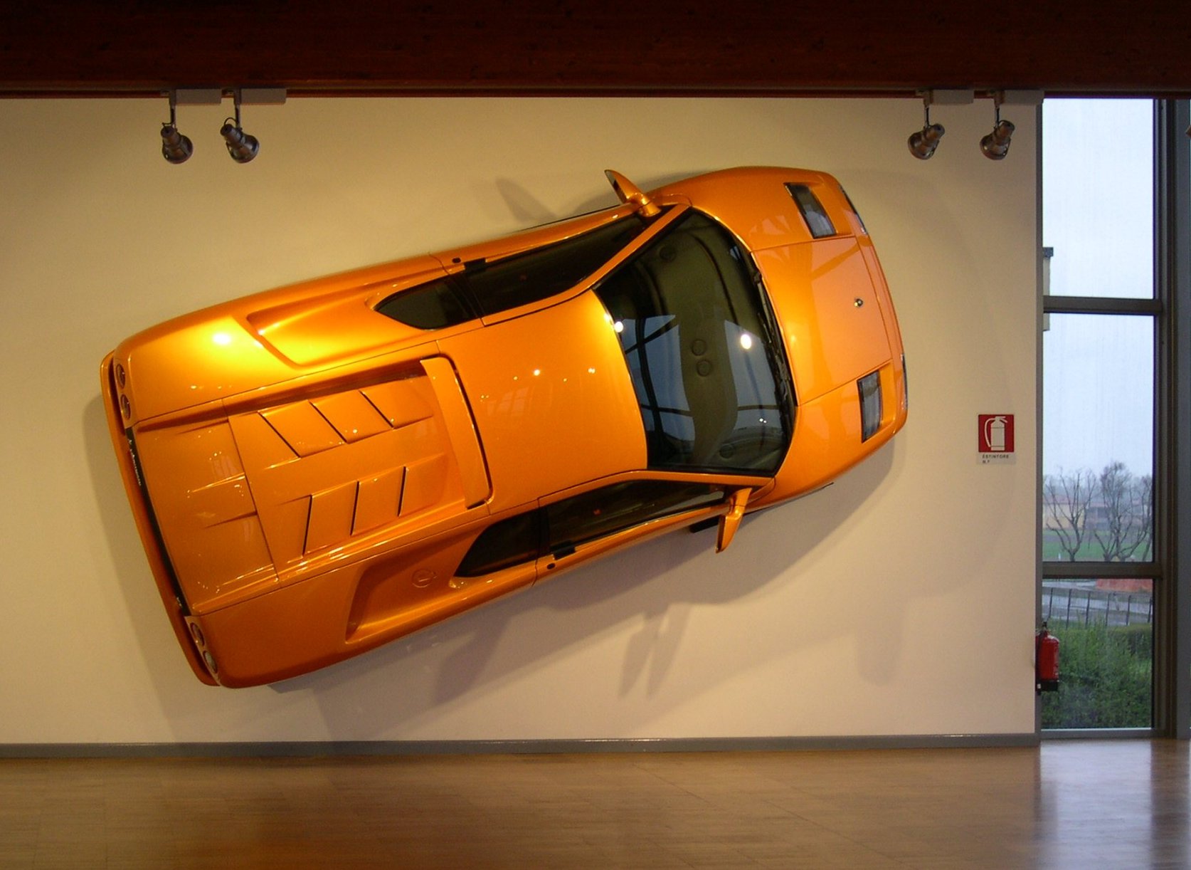 Lamborghini arancione esposta verticalmente a parete nel museo Lamborghini di Bologna