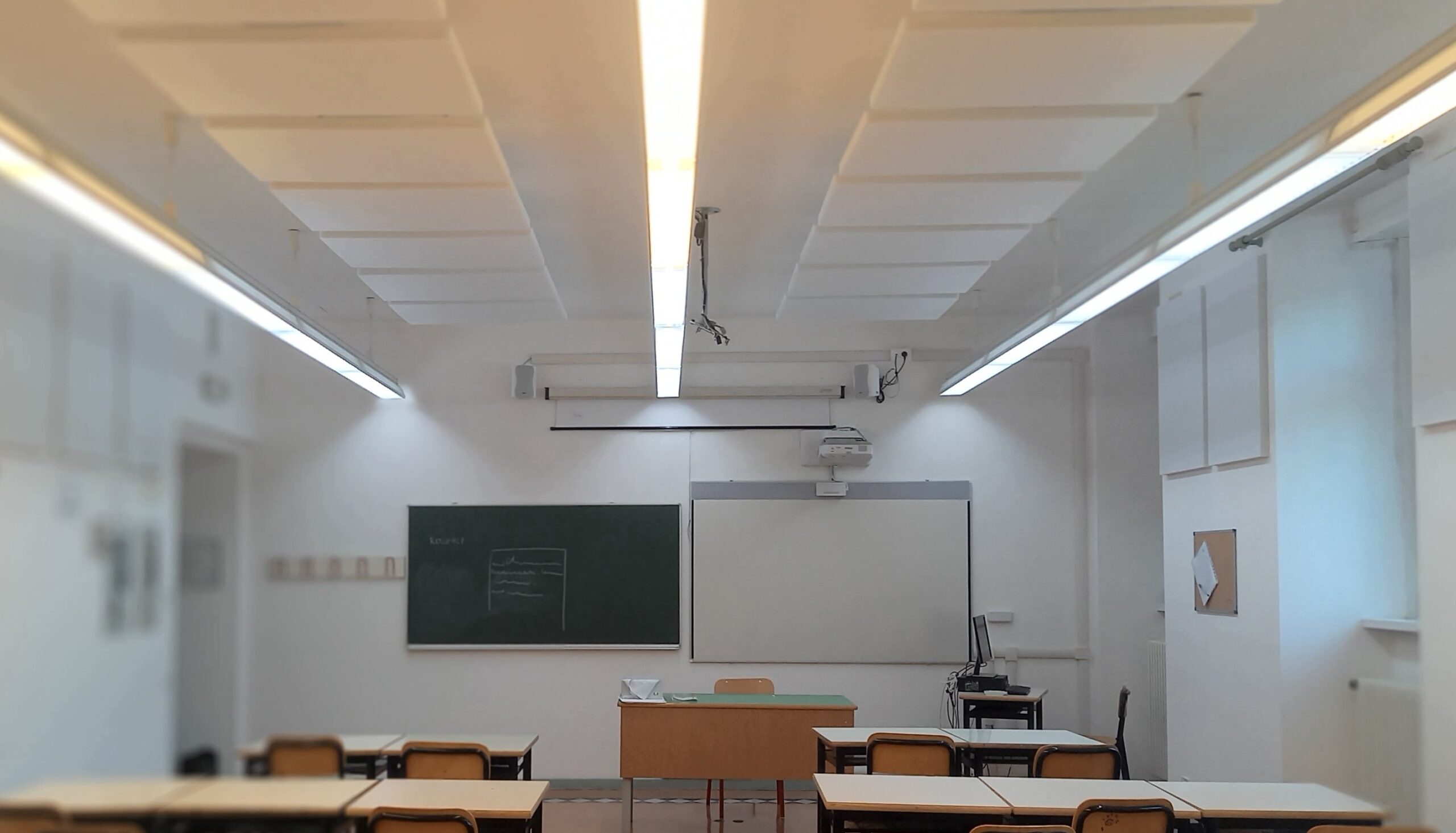 Aula del Liceo Galilei di Trento con pannelli fonoassorbenti a soffitto, lavagna e proiettore