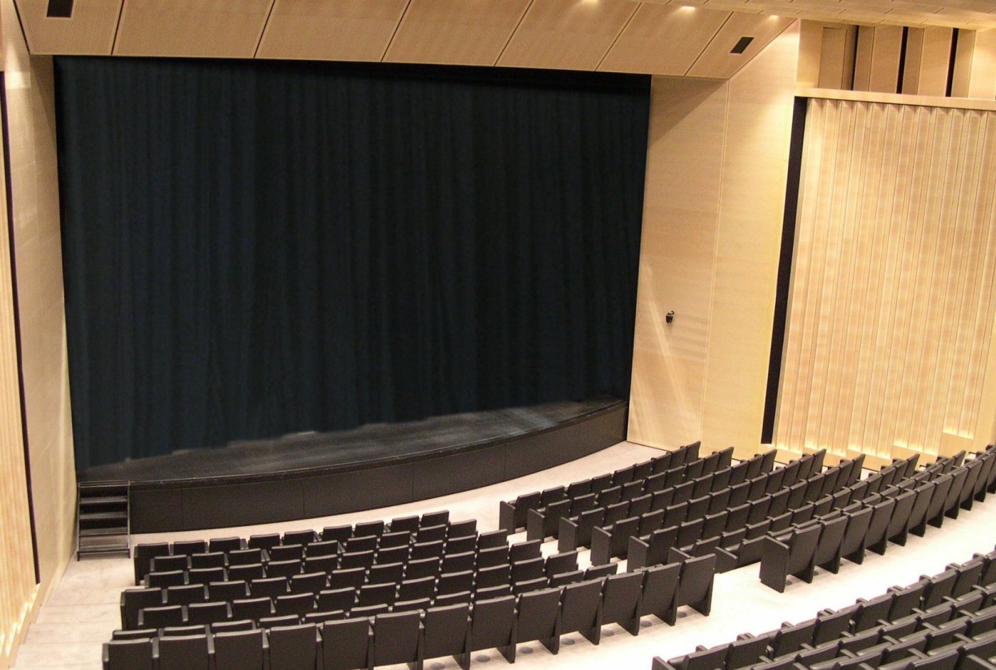 Auditorium del MART di Rovereto con palcoscenico, sipario scuro e pannelli acustici in legno