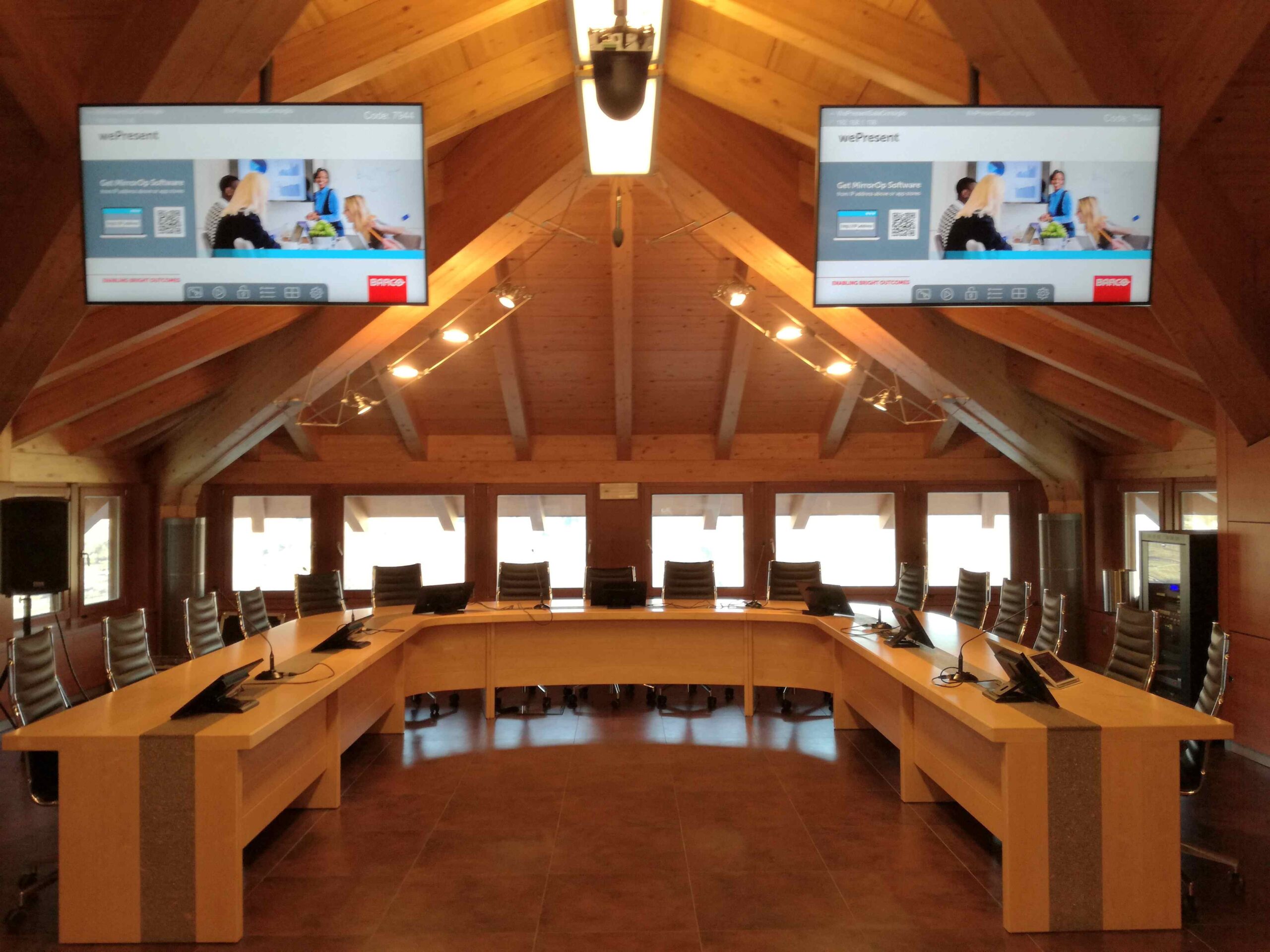 Sala consigliare di Albiano con tavolo a ferro di cavallo e doppio monitor a soffitto