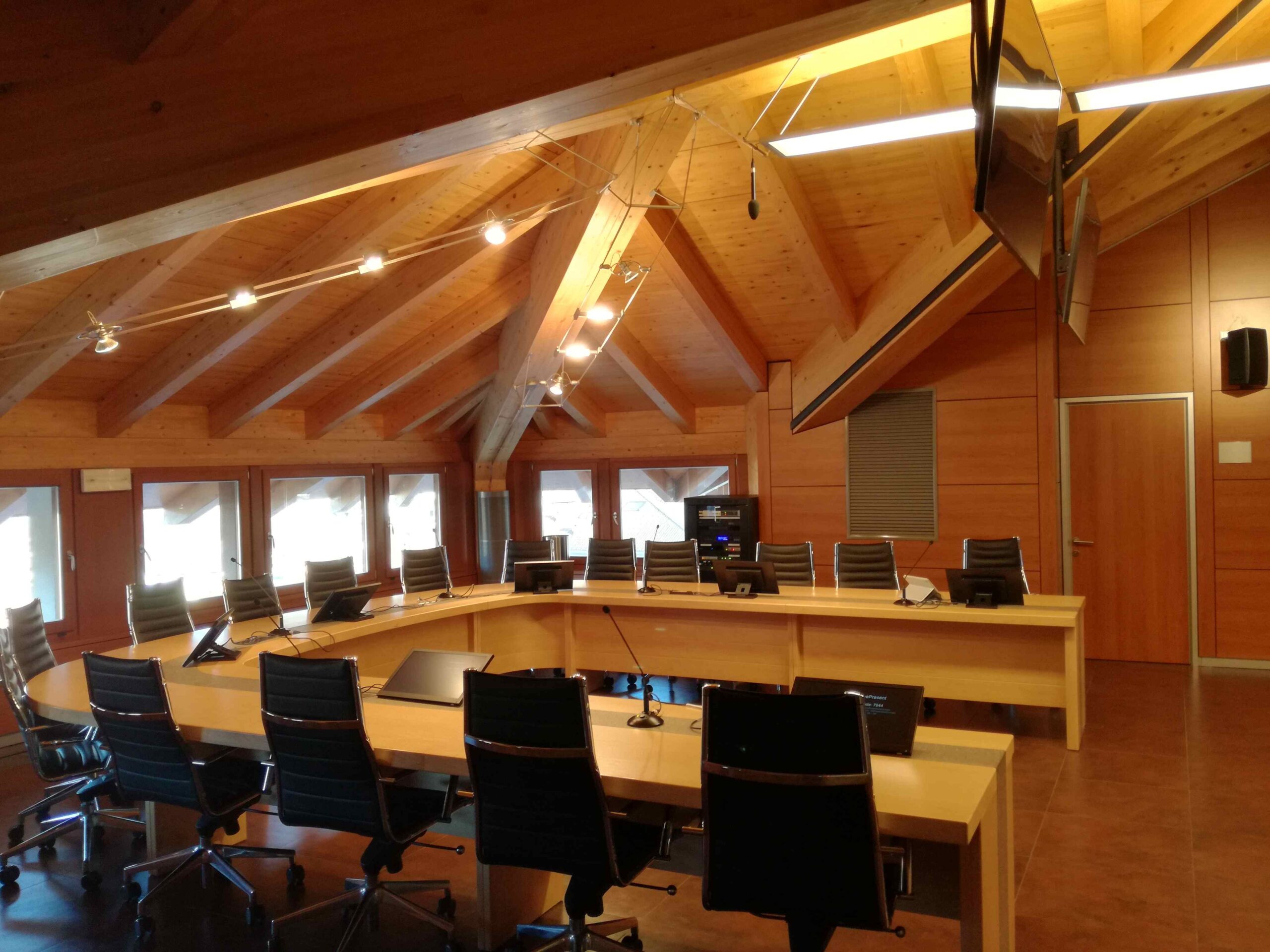 Vista laterale della sala consigliare di Albiano con postazioni microfono e tetto in legno