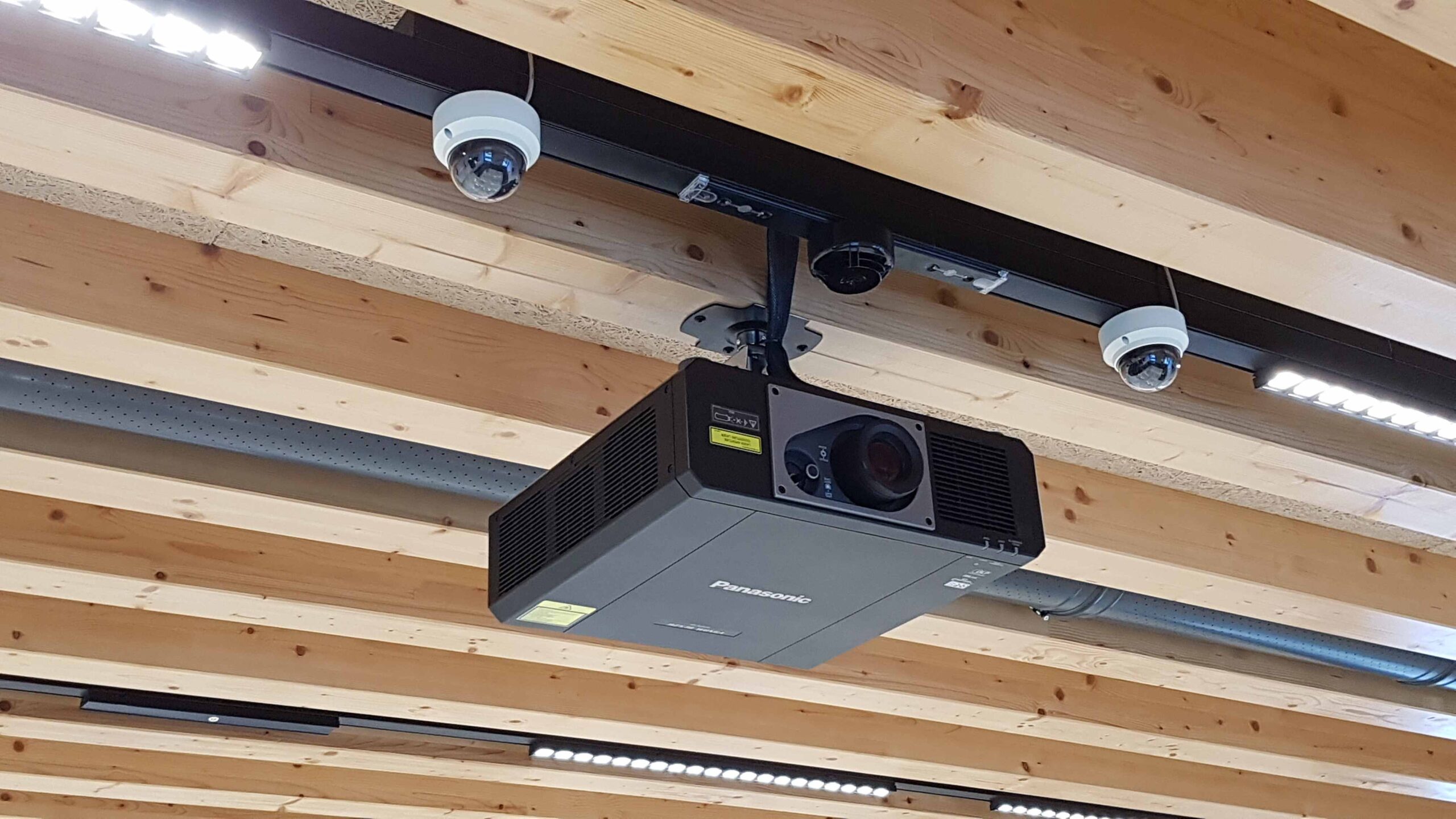 Videoproiettore Panasonic e telecamere dome installati a soffitto in legno nella sala consiliare di Torbole