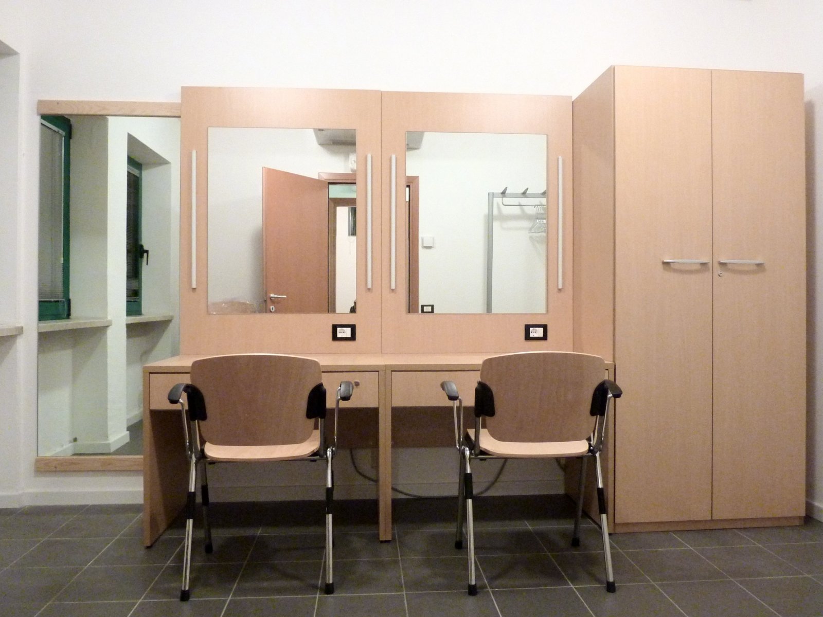 Camerino con postazioni trucco, specchi illuminati e armadio nella sala polifunzionale di Gardolo