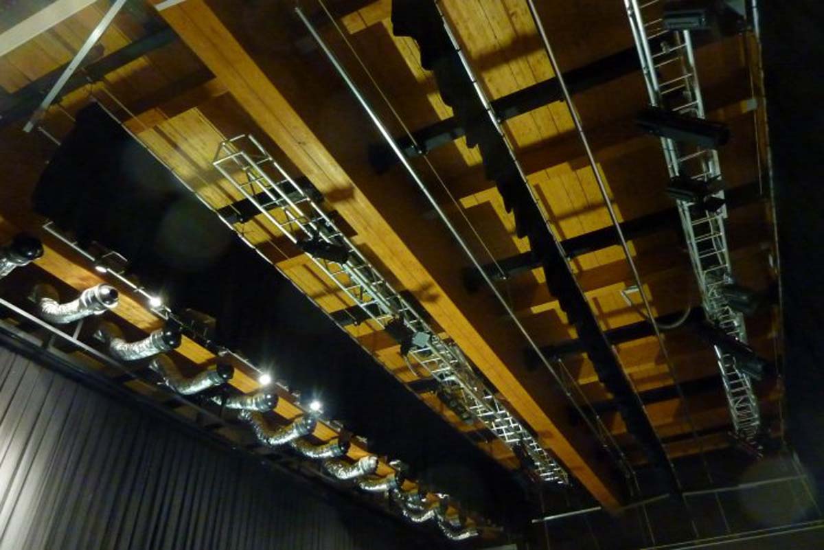 Soffitto con travi in legno, americane e fari teatrali nella sala polifunzionale Sanbapolis