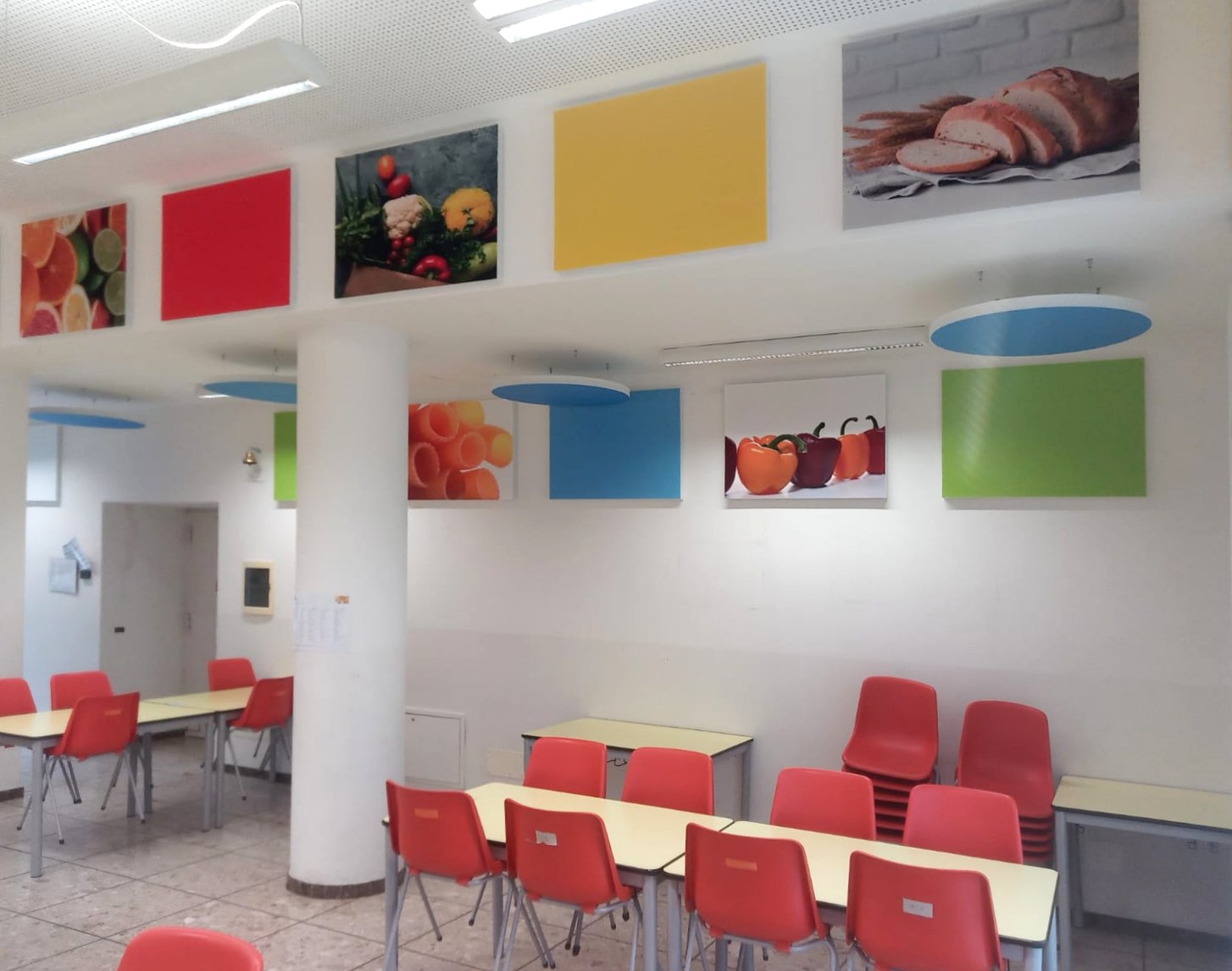 Pannelli fonoassorbenti colorati e dischi blu a soffitto nella mensa di Ville d'Anaunia