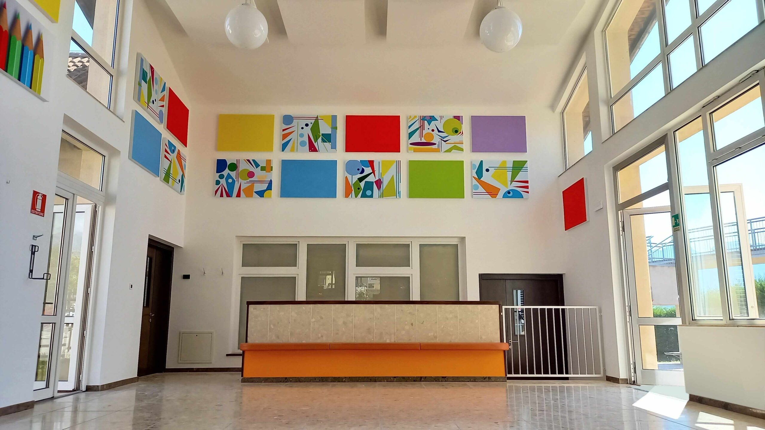 Atrio scuola primaria di Ville d'Anaunia con pannelli acustici colorati e illustrazioni a parete