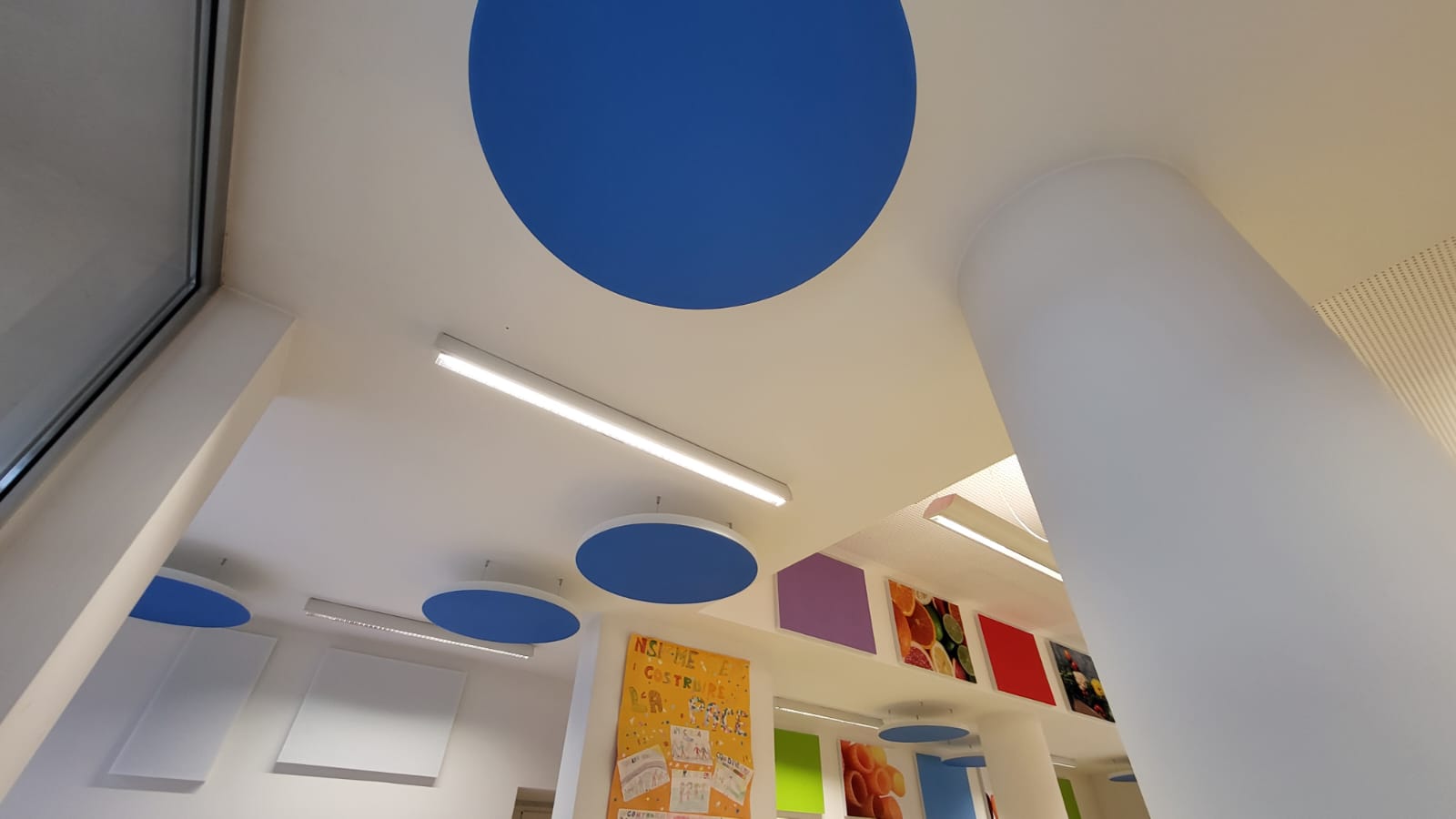 Dischi fonoassorbenti blu a soffitto e pannelli decorativi nella scuola primaria di Ville d'Anaunia