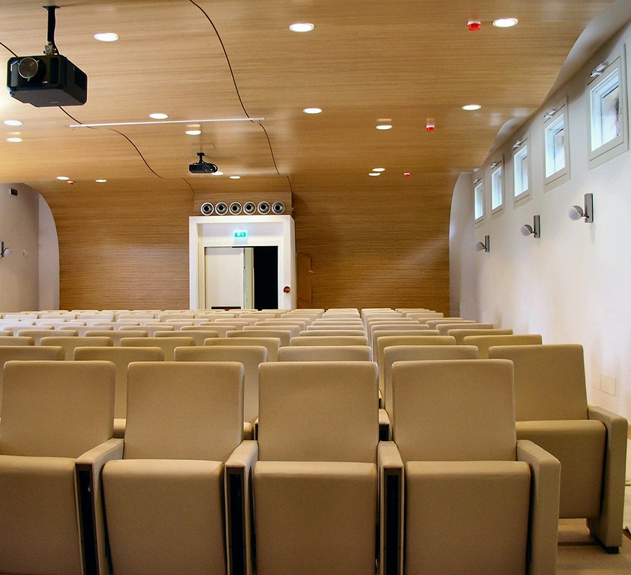 Auditorium Segafredo con poltrone beige, soffitto curvo in legno e videoproiettore a soffitto