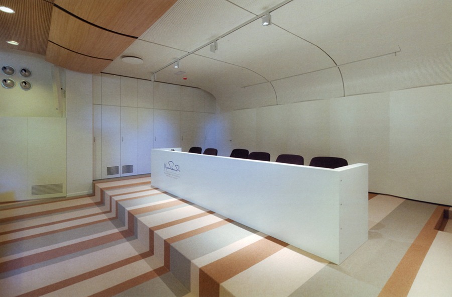 Palco relatori con banco e gradinate nell'auditorium Segafredo con pavimento a fasce colorate