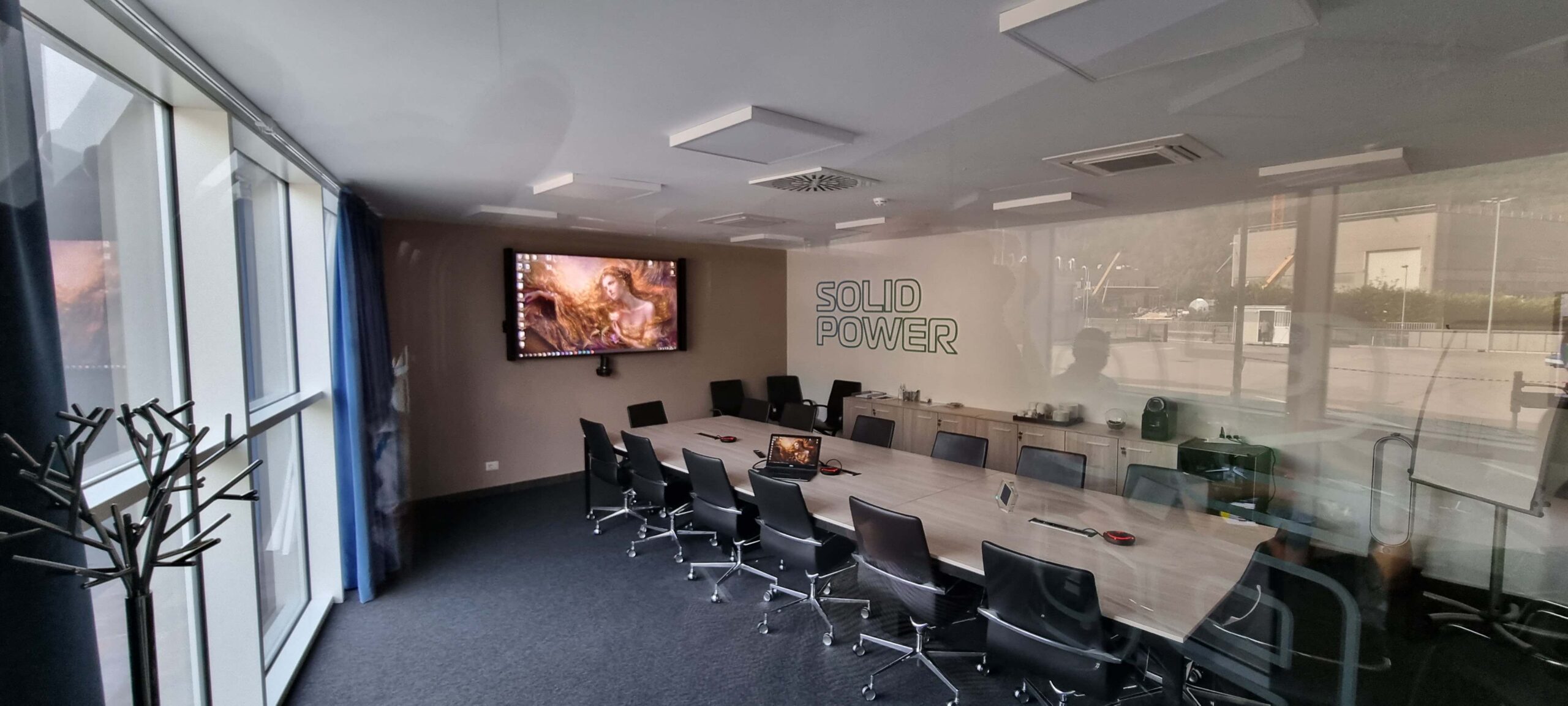 Sala riunioni Solid Power a Pergine con display interattivo, tavolo conferenze e pannelli fonoassorbenti a soffitto