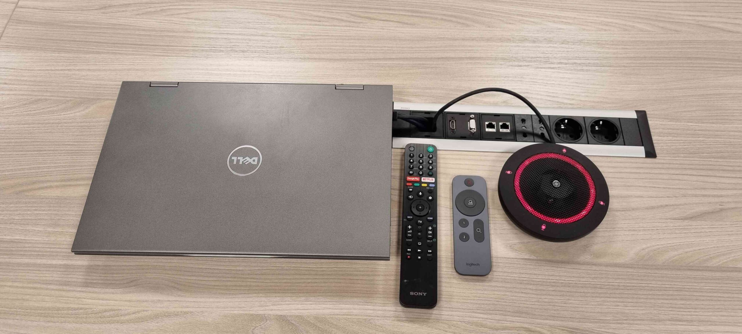 Dettaglio laptop Dell, telecomando Sony e microfono da conferenza sul tavolo riunioni Solid Power Pergine