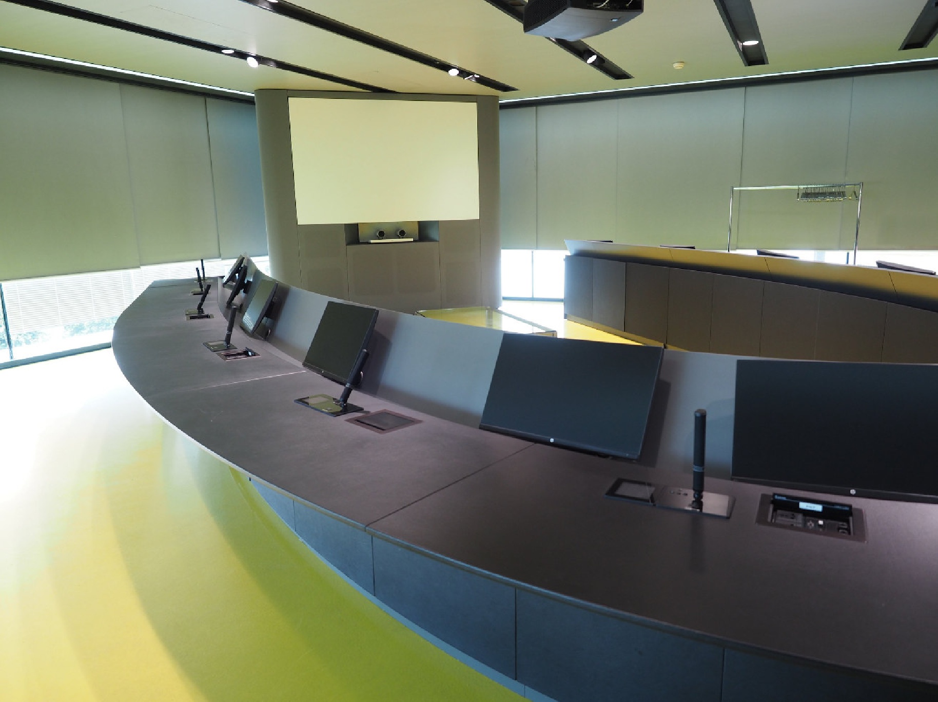 Tavolo riunioni Top Class curvo con monitor reclinabili, schermo di proiezione e sistema di controllo