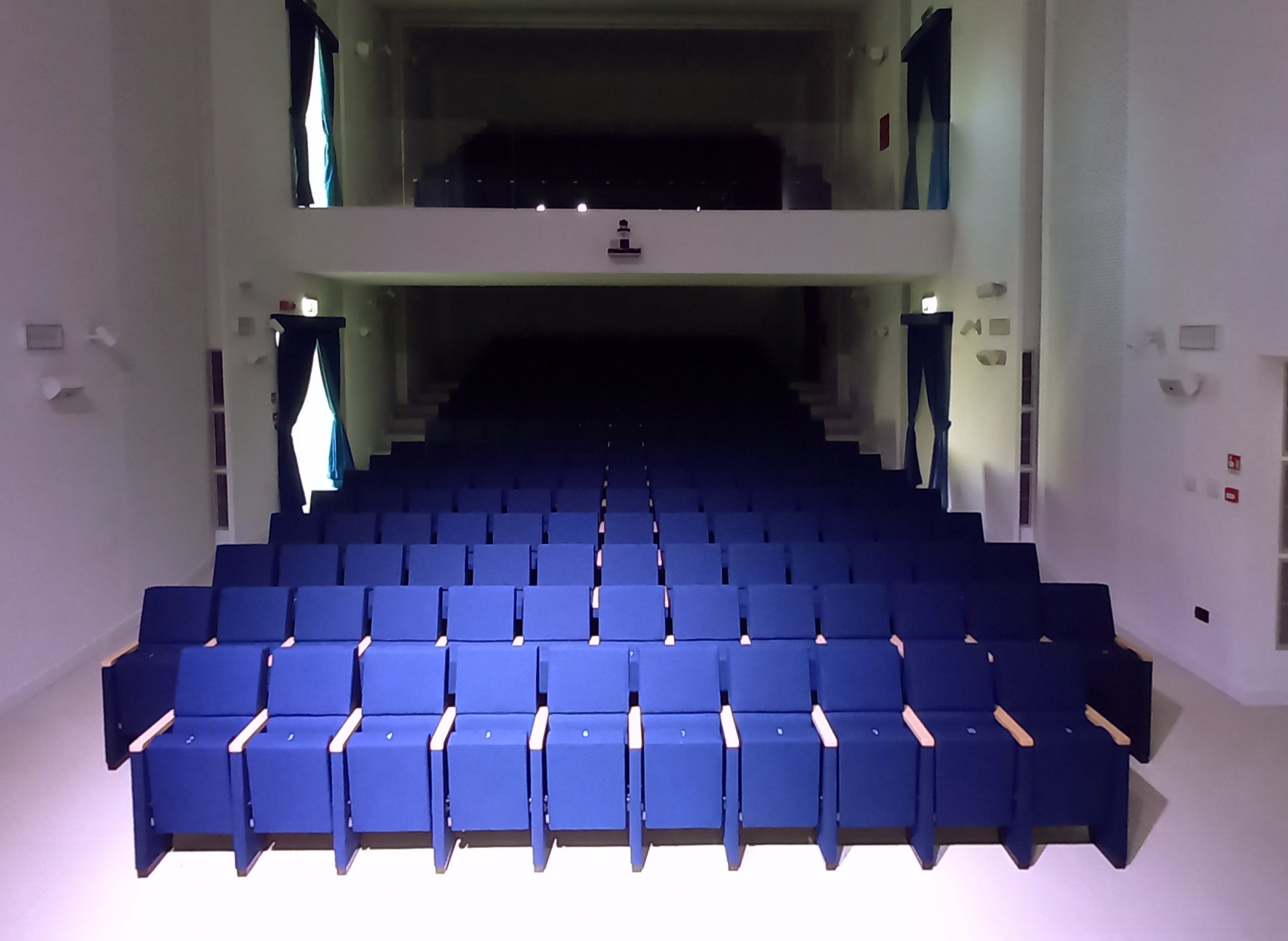 Vista frontale della platea del teatro di Calcinato con poltrone blu e balconata superiore