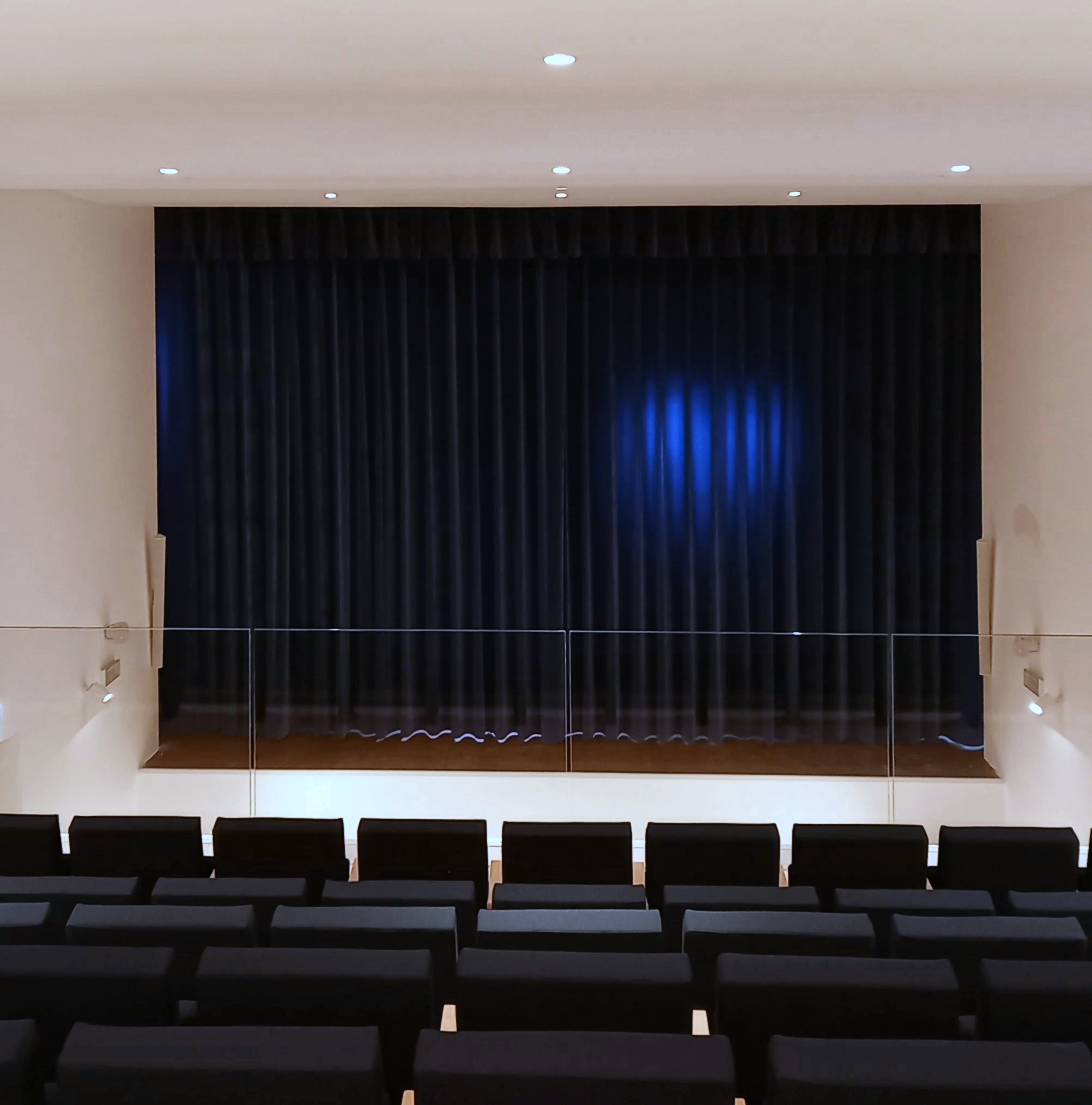 Palcoscenico del teatro di Calcinato con sipario scuro illuminato da luce blu e poltrone in platea